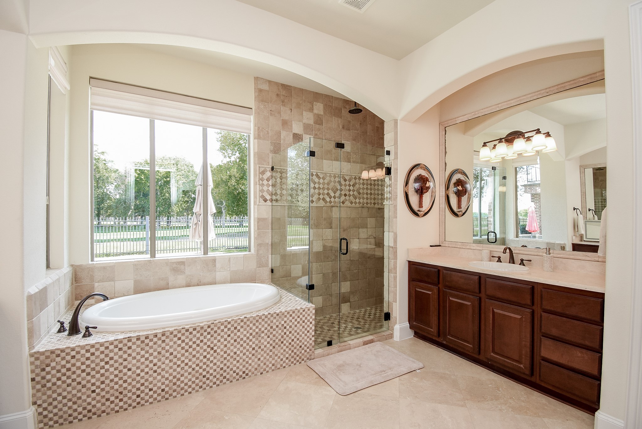 The views in this home just don't stop. Primary suite with soaking tub, frameless shower and two large vanities one of which is shown in this photo. The arches add architectural detail to the room.