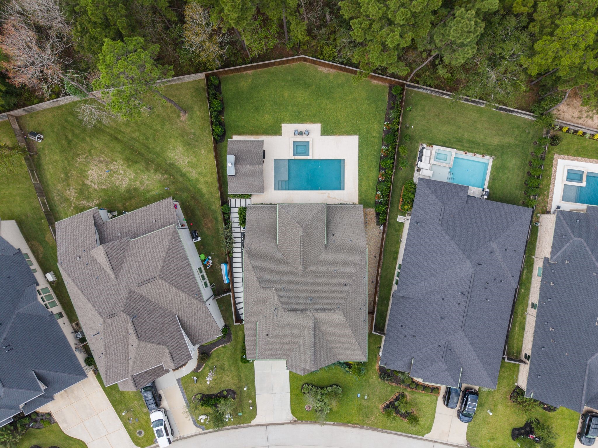 Aerial views highlight the homes impressive oversized homesite, custom professional hardscaping along the side yard, and a wooded easement behind the property that enhances privacywhile still offering an expansive lawn beyond the pool, spa, and cabana for added space to play, relax, and entertain.