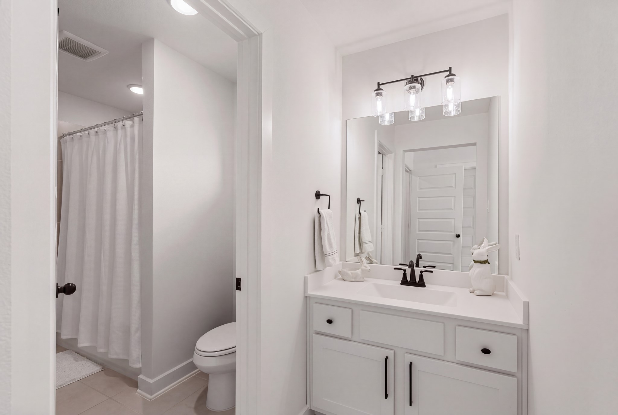 Conveniently designed Hollywood-style bath featuring private vanity areas, elegant quartz countertops, designer lighting, and stylish dark fixturesoffering both comfort and functionality for the upstairs bedrooms!
