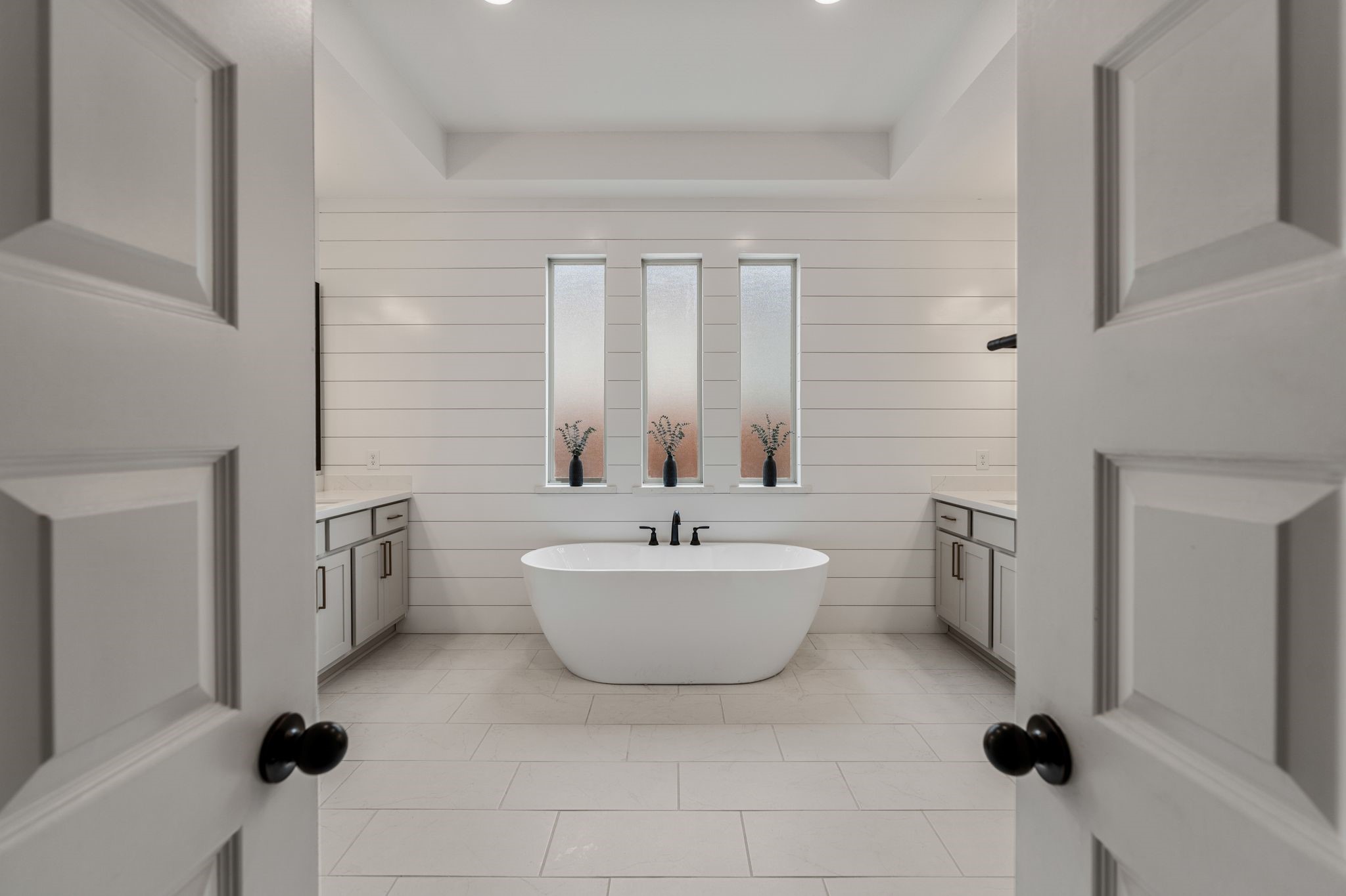 Luxurious, spa-inspired primary bath featuring a stunning freestanding soaking tub, elegant shiplap accent wall