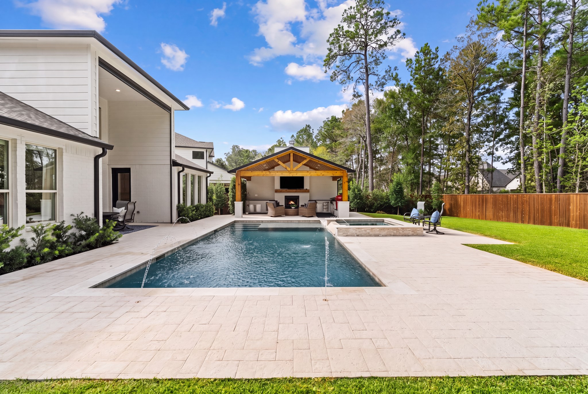 Spectacular resort-style backyard oasis featuring a heated pool and raised spa, expansive travertine decking, and lush landscaping, all surrounded by an unusually large, private backyard backing to a serene wooded greenbelt. Perfect for year-round relaxation and entertaining!