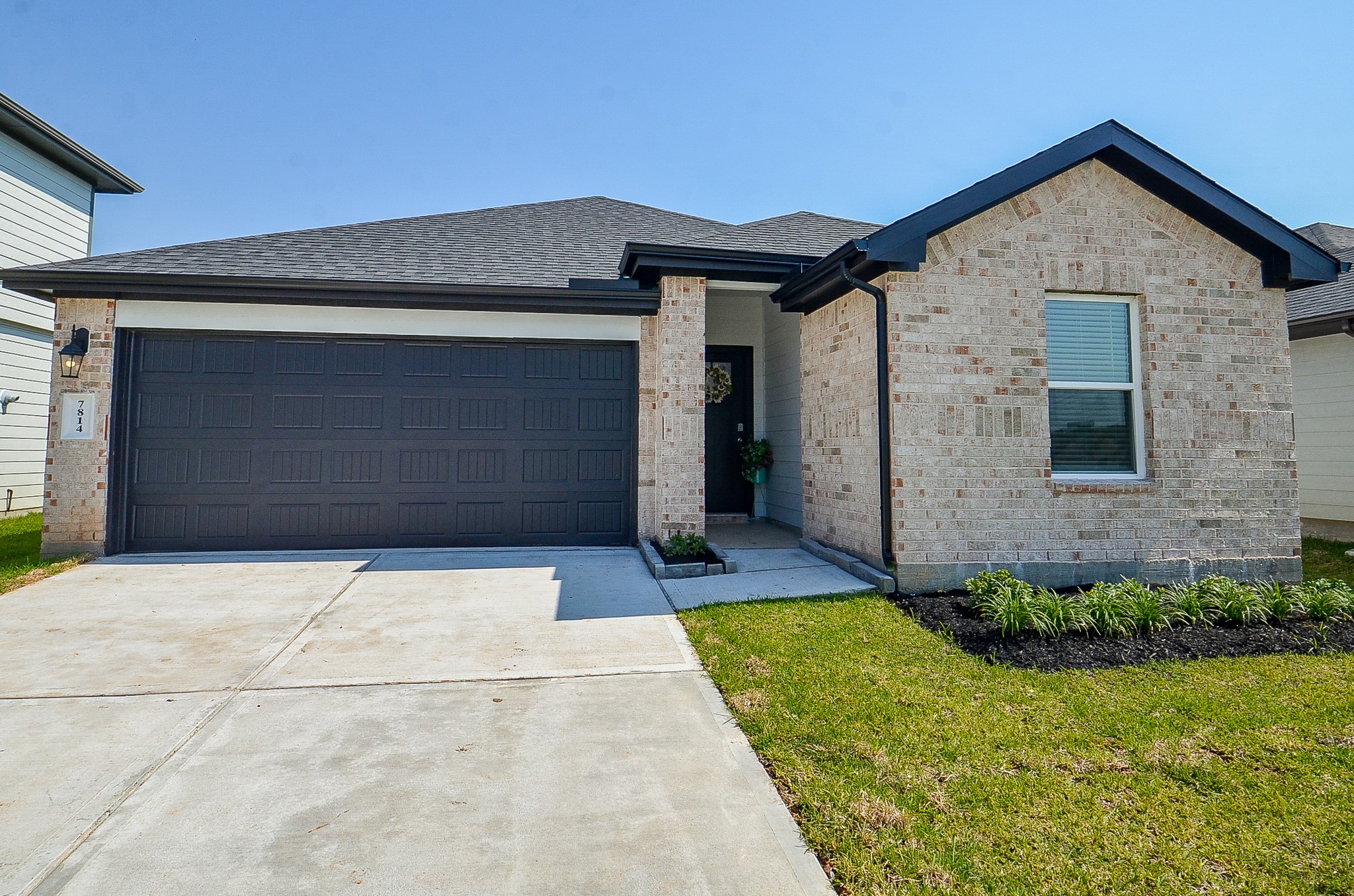 Charming single-story home featuring a modern brick exterior, double garage, and a welcoming front entry with landscaped garden accents.