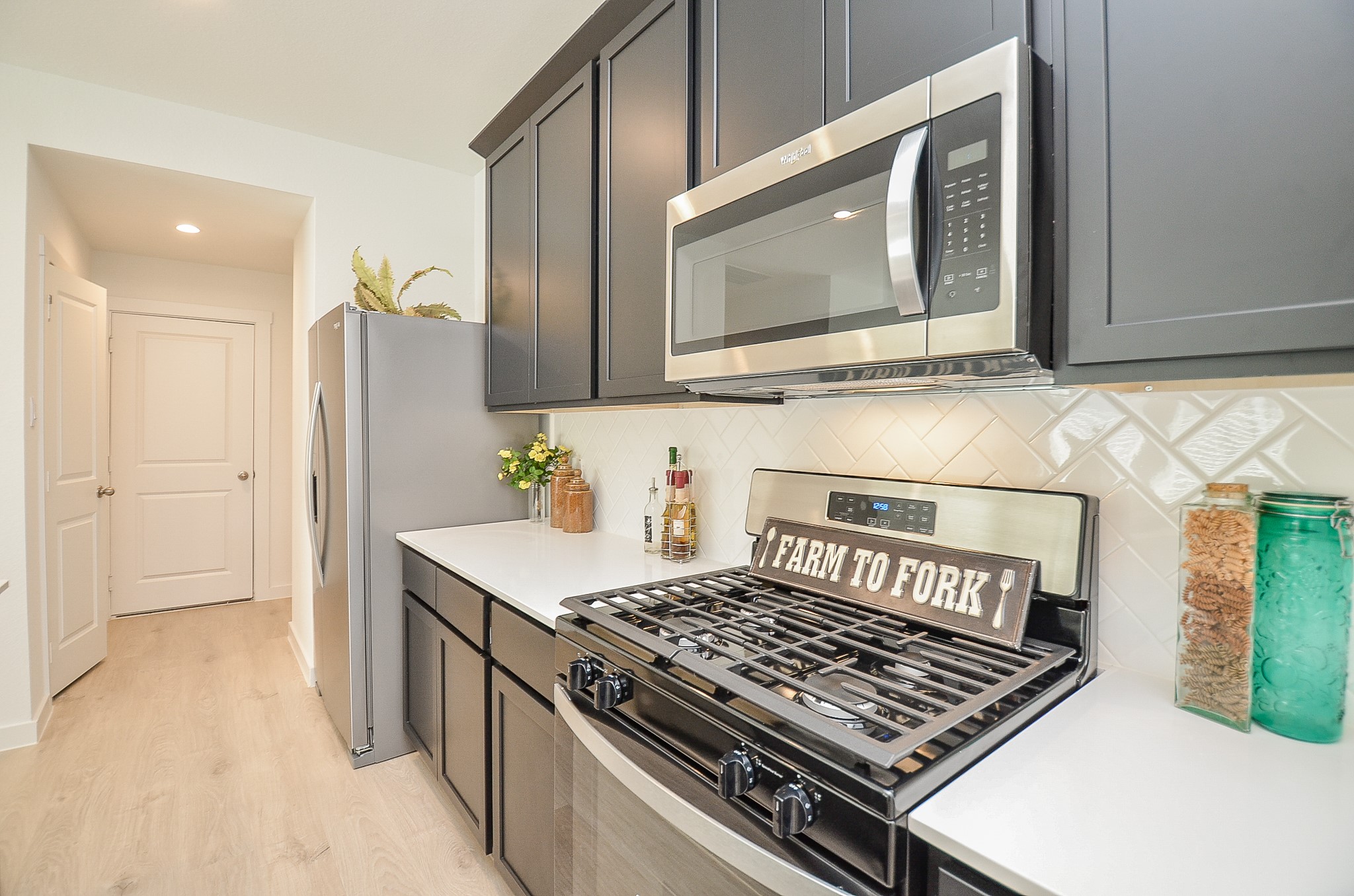 Modern kitchen featuring sleek stainless steel appliances, elegant dark cabinetry, and a stylish herringbone backsplash.