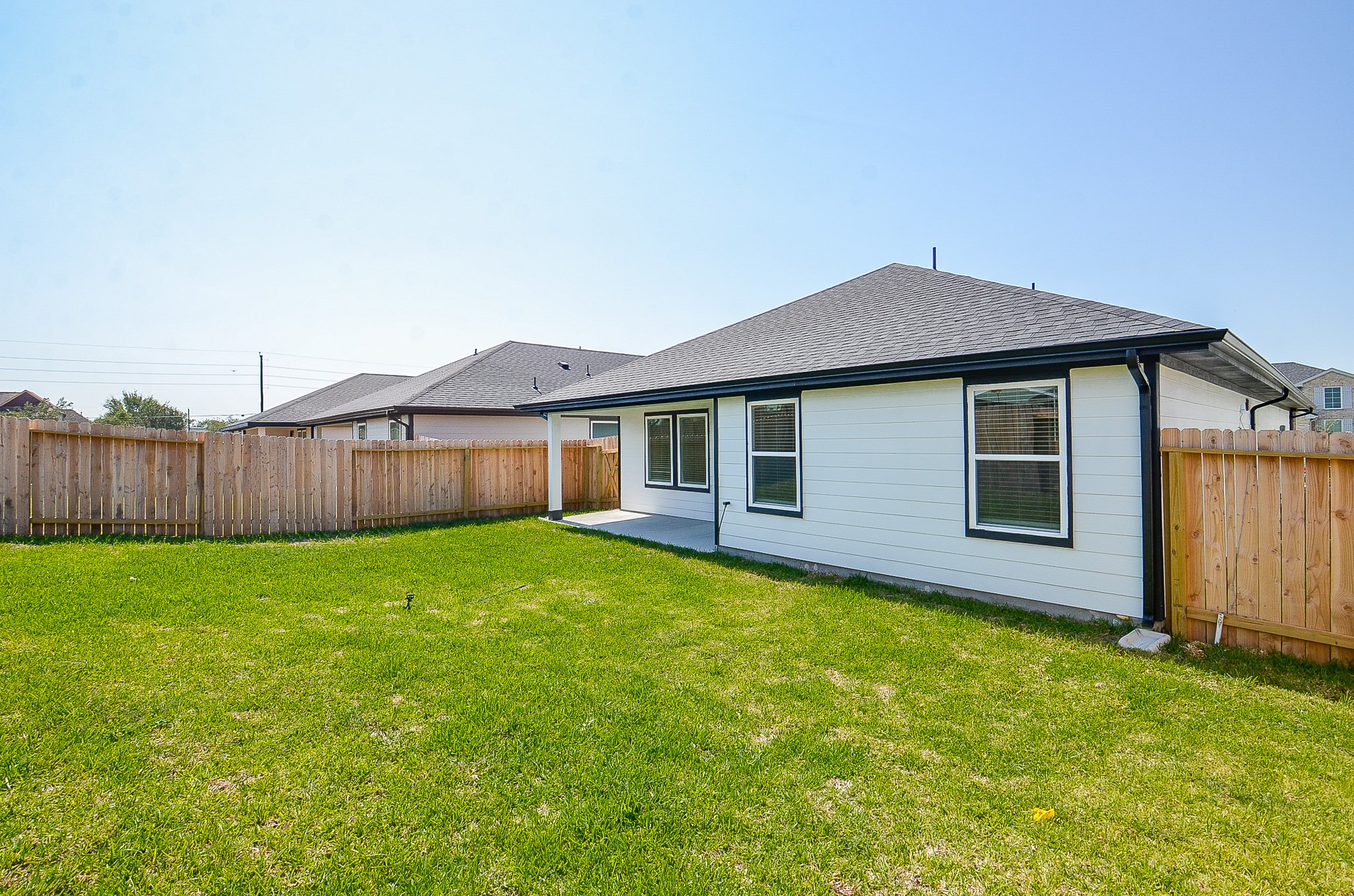 Spacious backyard with lush green grass and a wooden fence, perfect for outdoor activities and privacy.