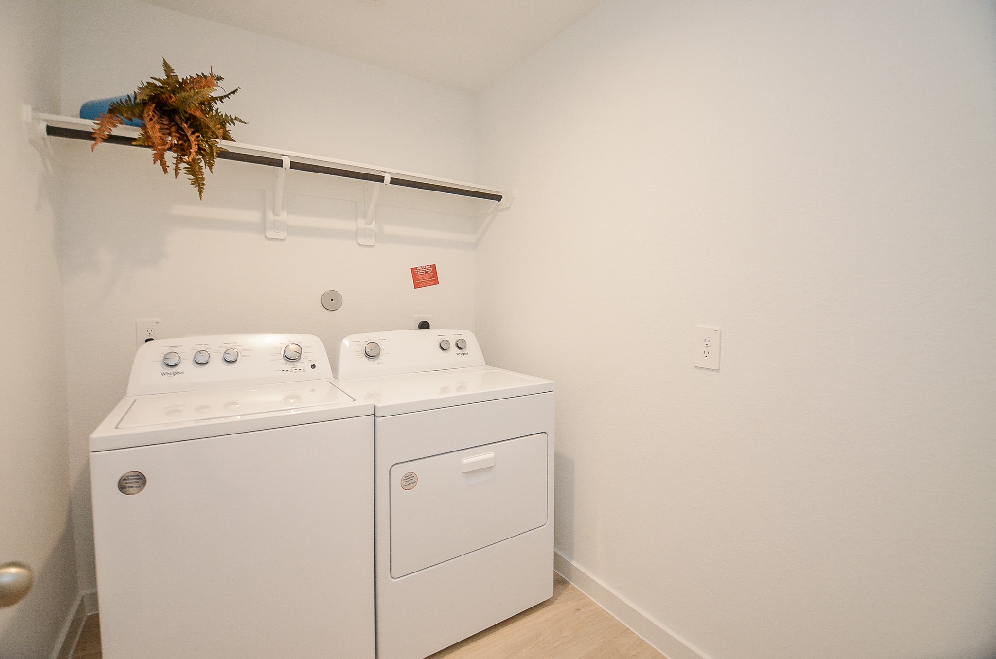 Bright and functional laundry room featuring modern washer and dryer, with a convenient overhead shelf for storage.