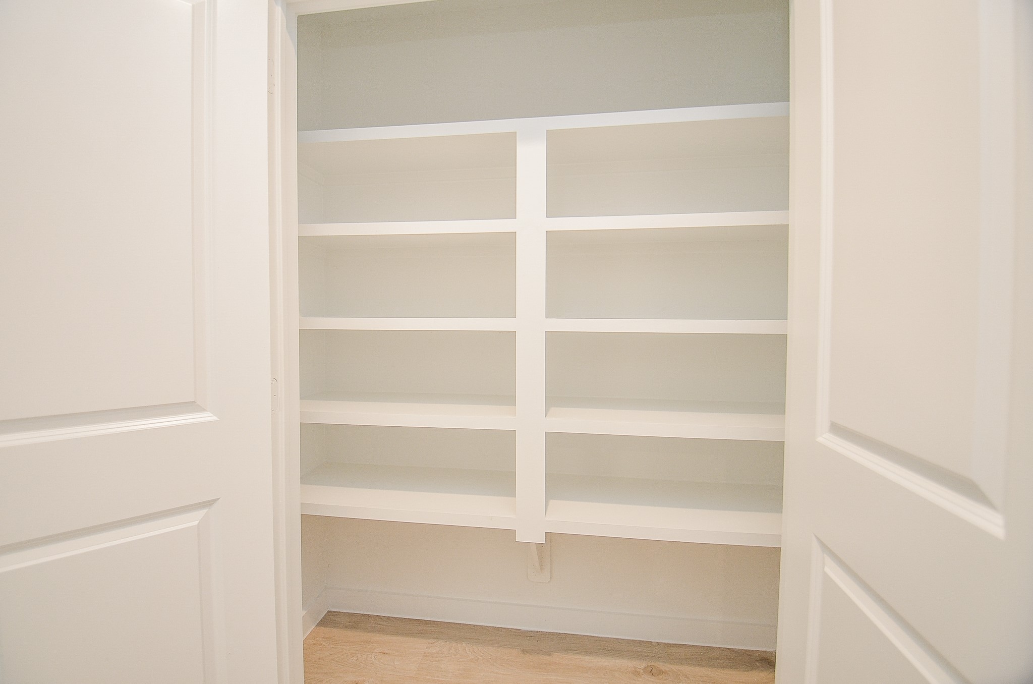 Spacious pantry with sleek white shelving, perfect for organized storage and easy access to kitchen essentials.