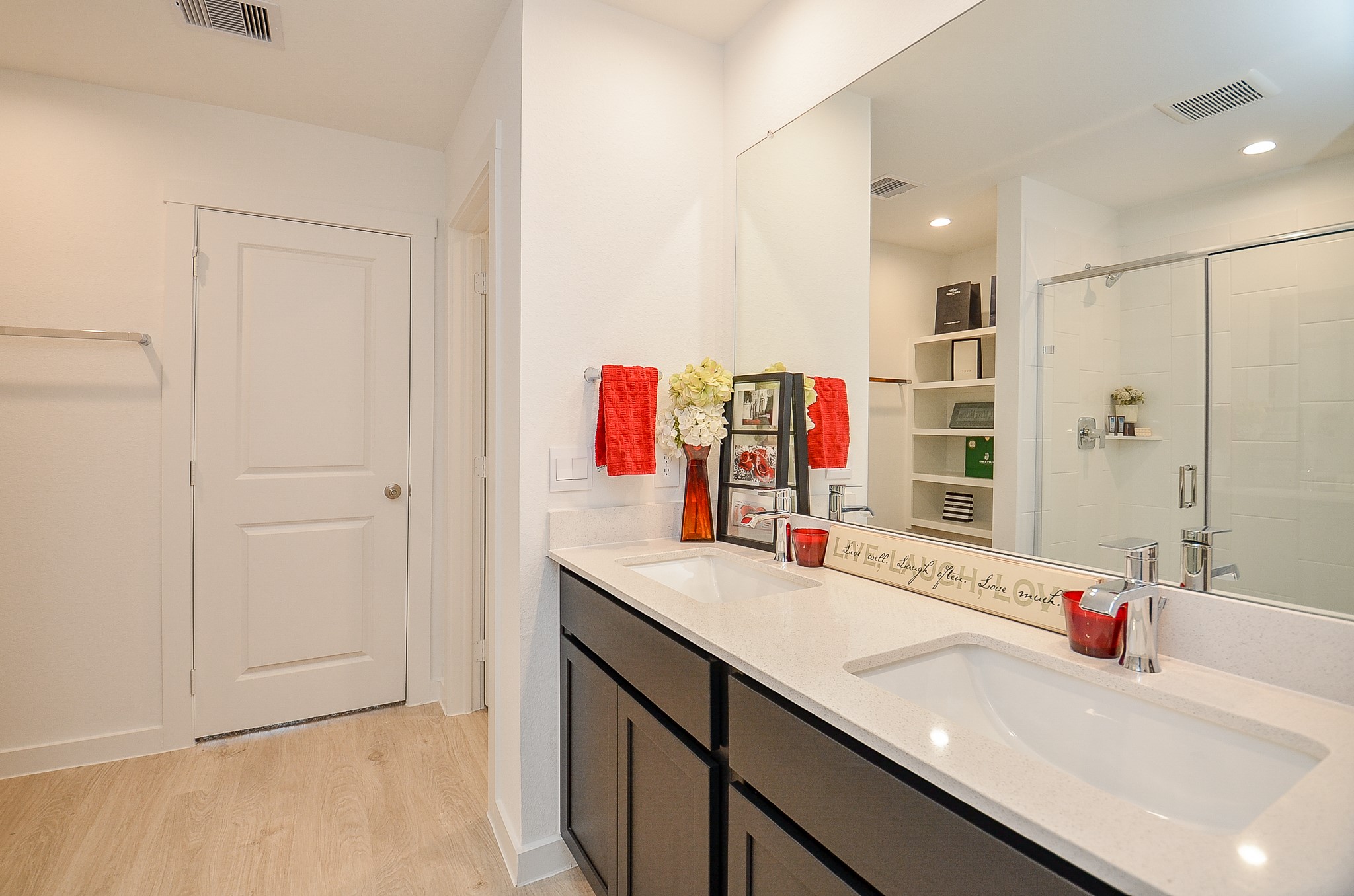 Modern bathroom featuring a dual-sink vanity with sleek countertops, spacious glass-enclosed shower and ample storage.