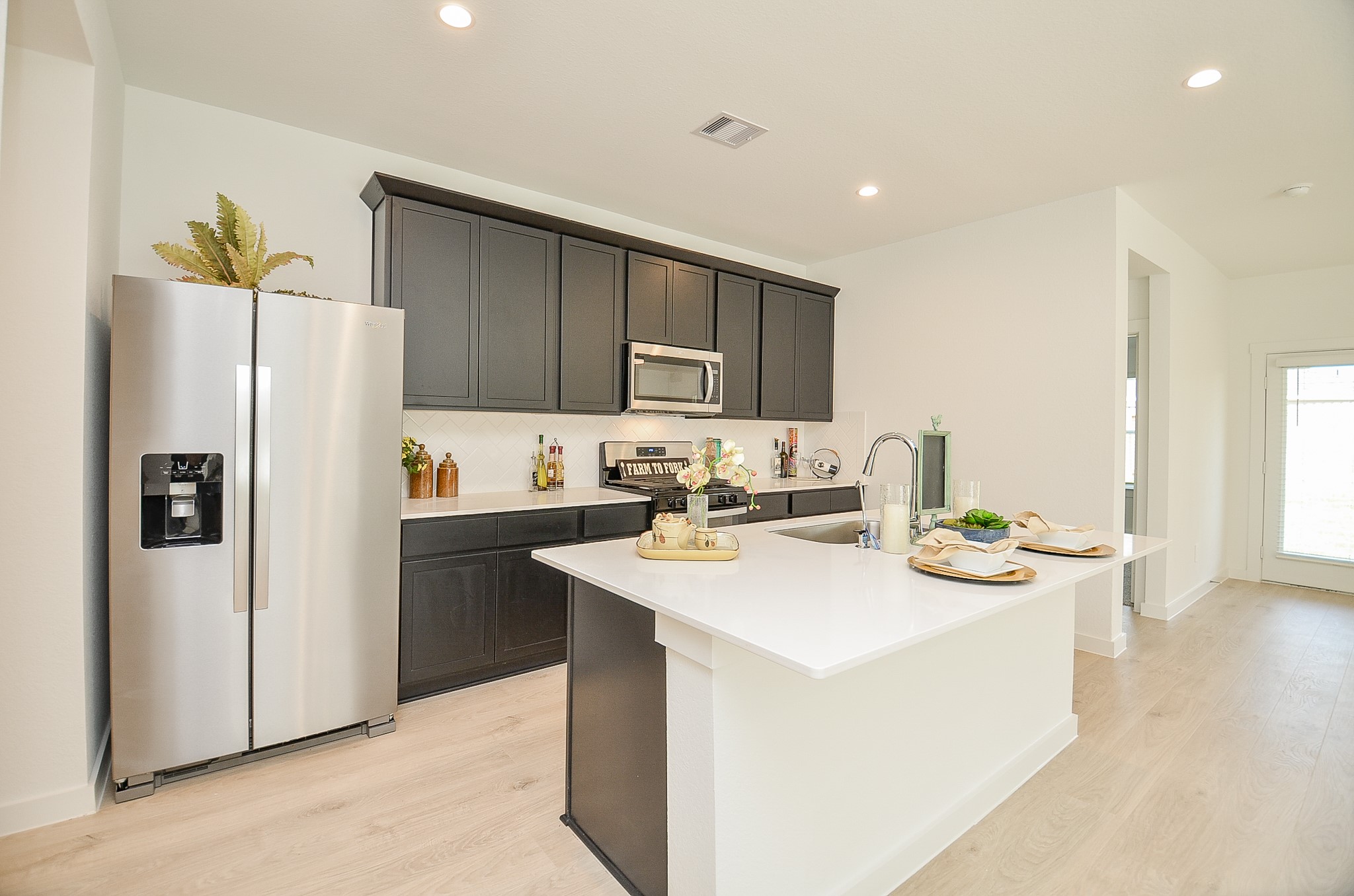 Modern kitchen with sleek dark cabinetry, stainless steel appliances, and a spacious white island perfect for dining and entertaining.
