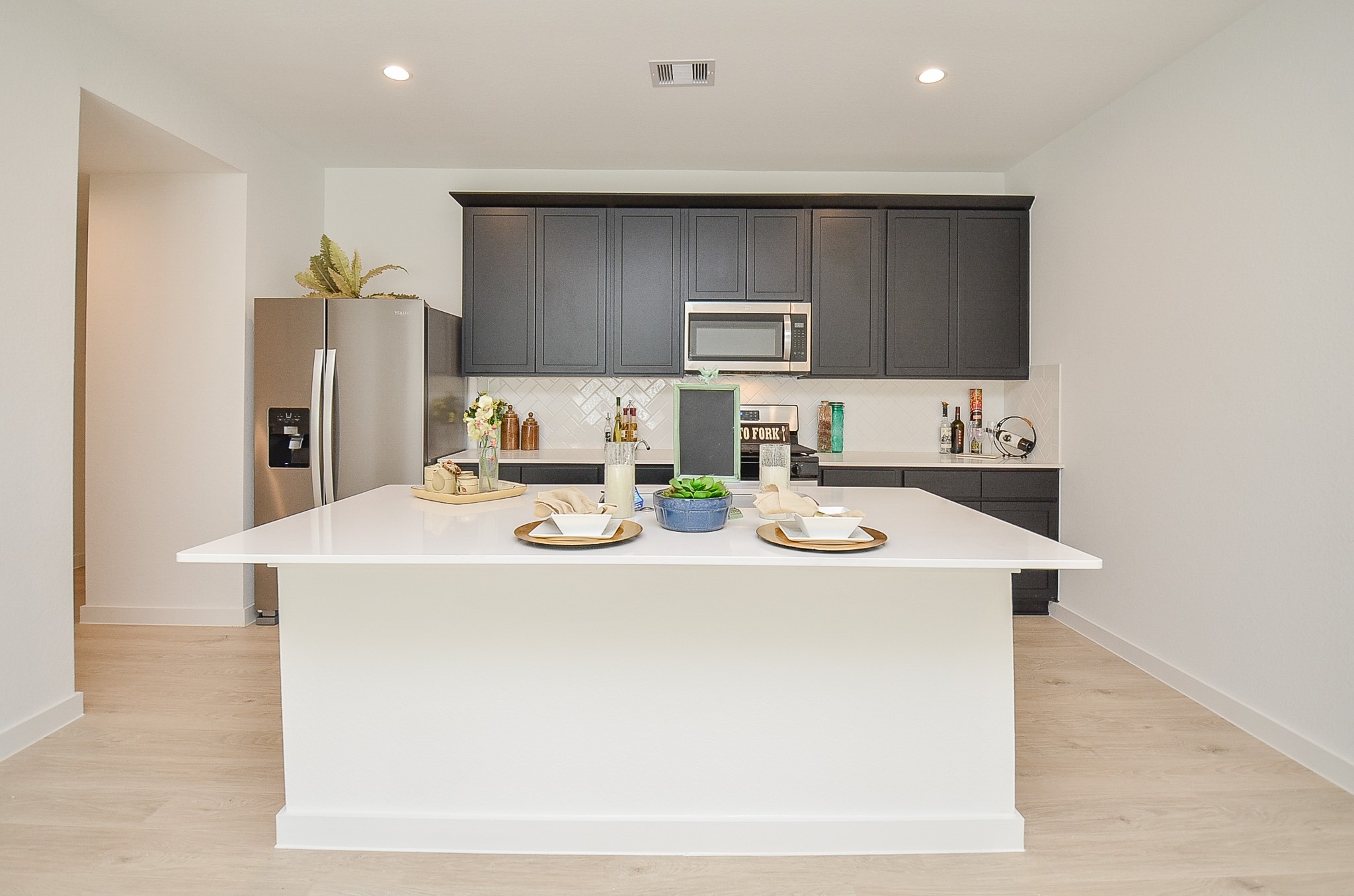 Sleek modern kitchen featuring a spacious island with elegant countertops, dark cabinetry, stainless steel appliances, and stylish accents for a contemporary feel.