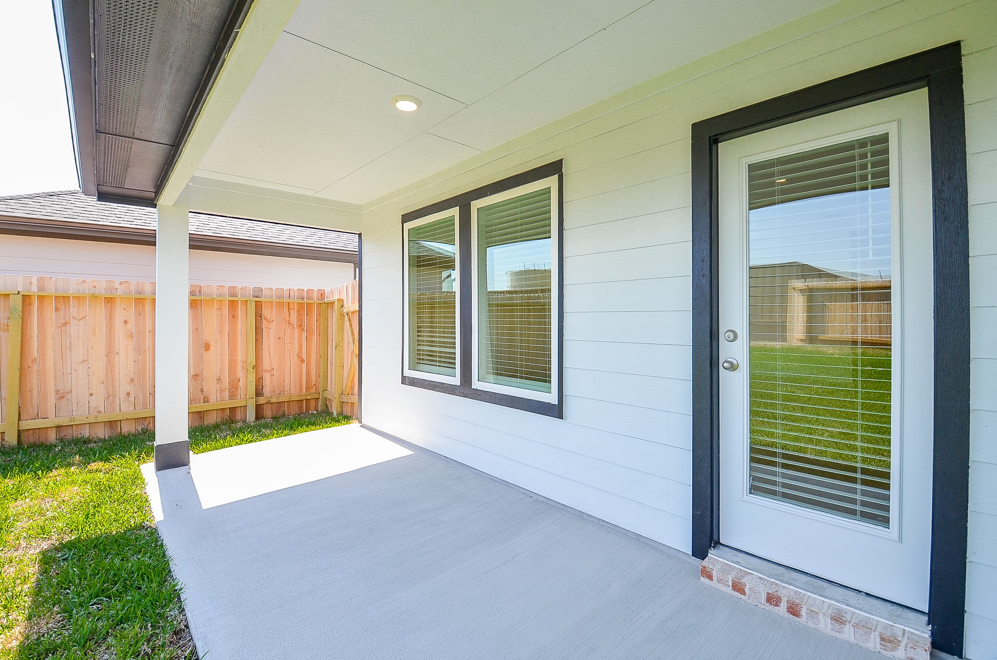 Charming covered patio with clean lines and ample natural light, perfect for relaxing and enjoying the private fenced yard.
