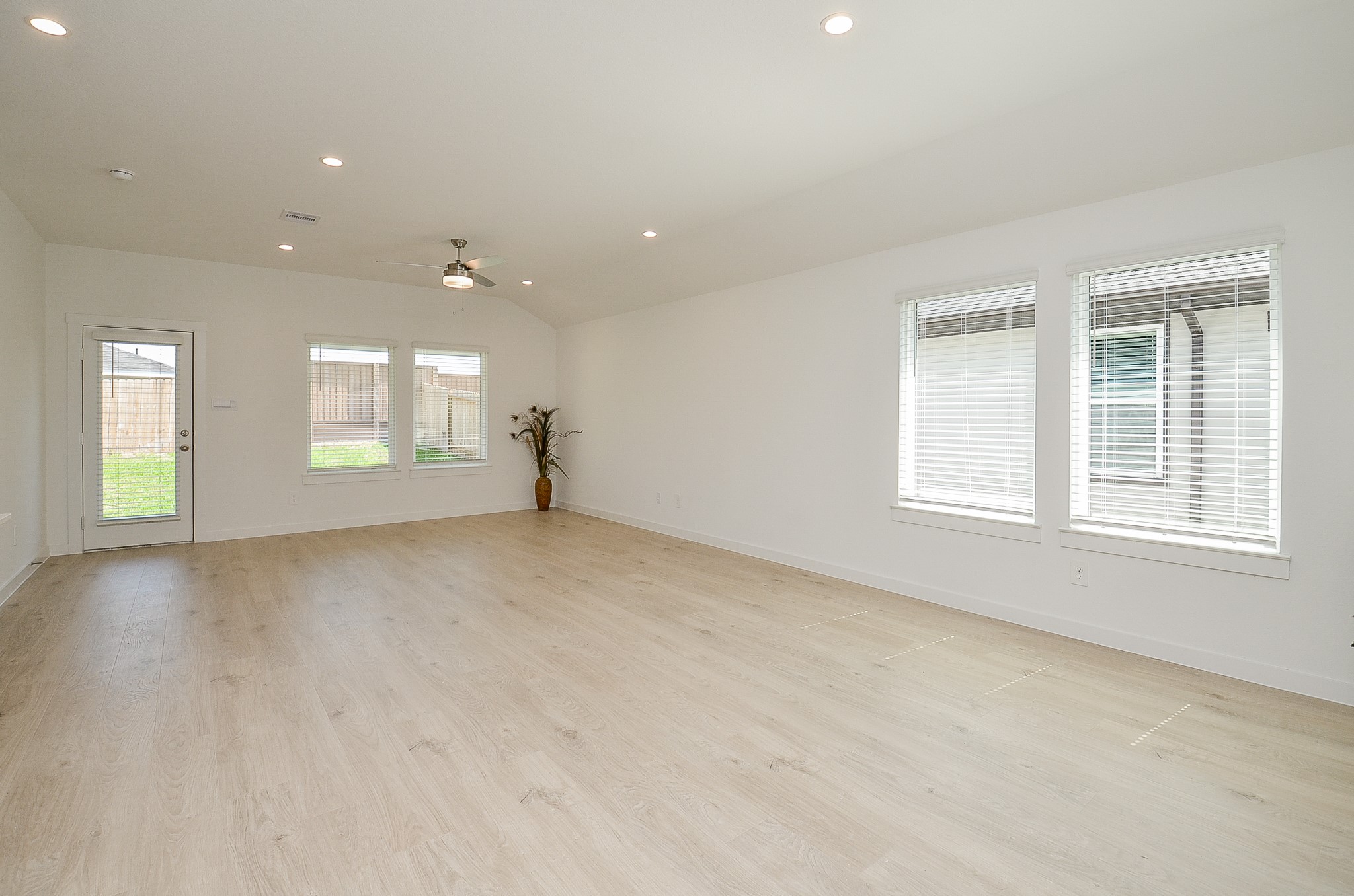Spacious and bright living area with sleek wood flooring, recessed lighting, and large windows offering abundant natural light.