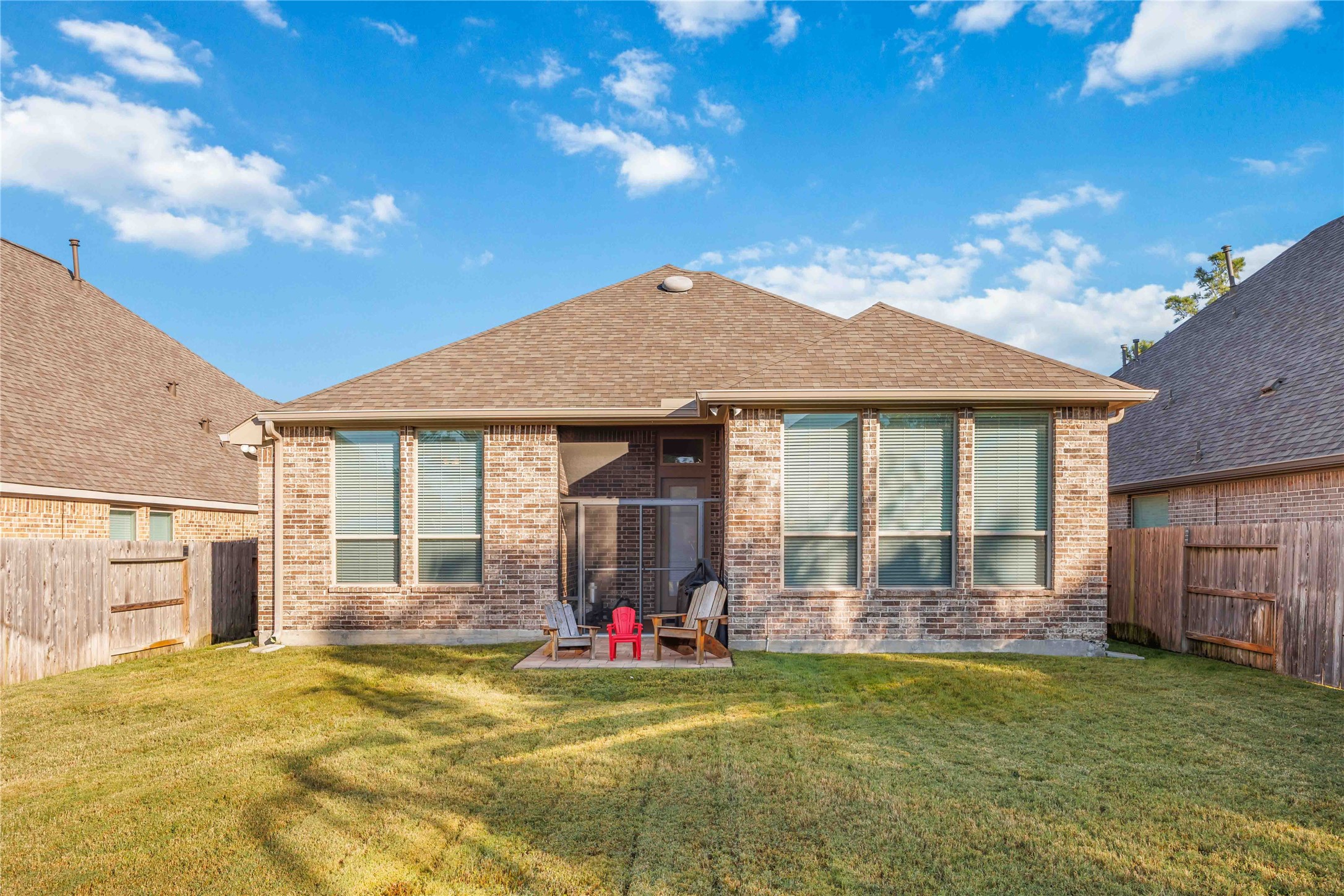 This is a charming single-story brick home with a spacious backyard. The property features a small patio area, perfect for outdoor seating. It offers privacy with fenced boundaries and has well-maintained grass, ideal for relaxation or play.