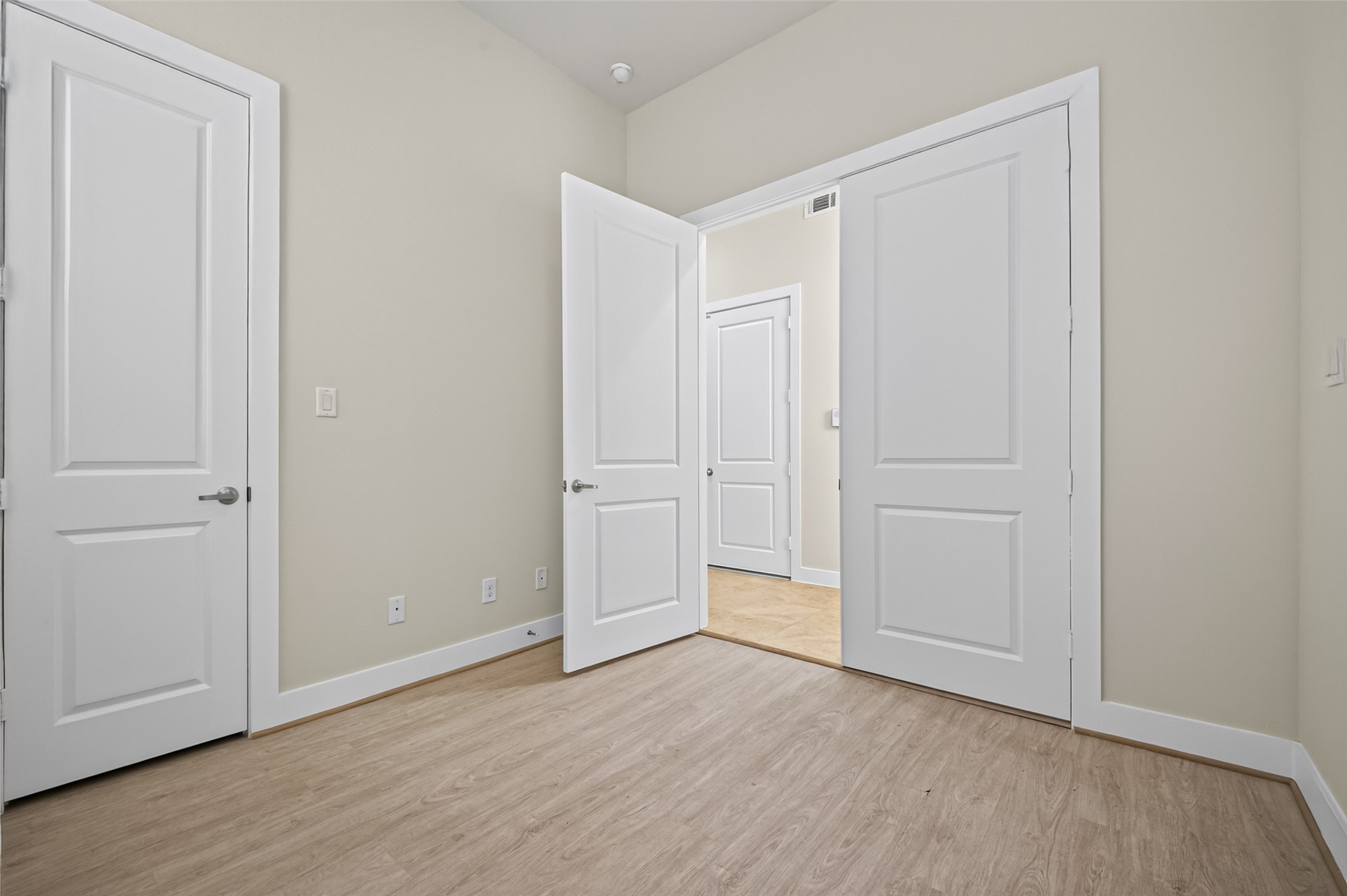 Bright room with light wood flooring and crisp white doors, offering a clean and modern atmosphere.