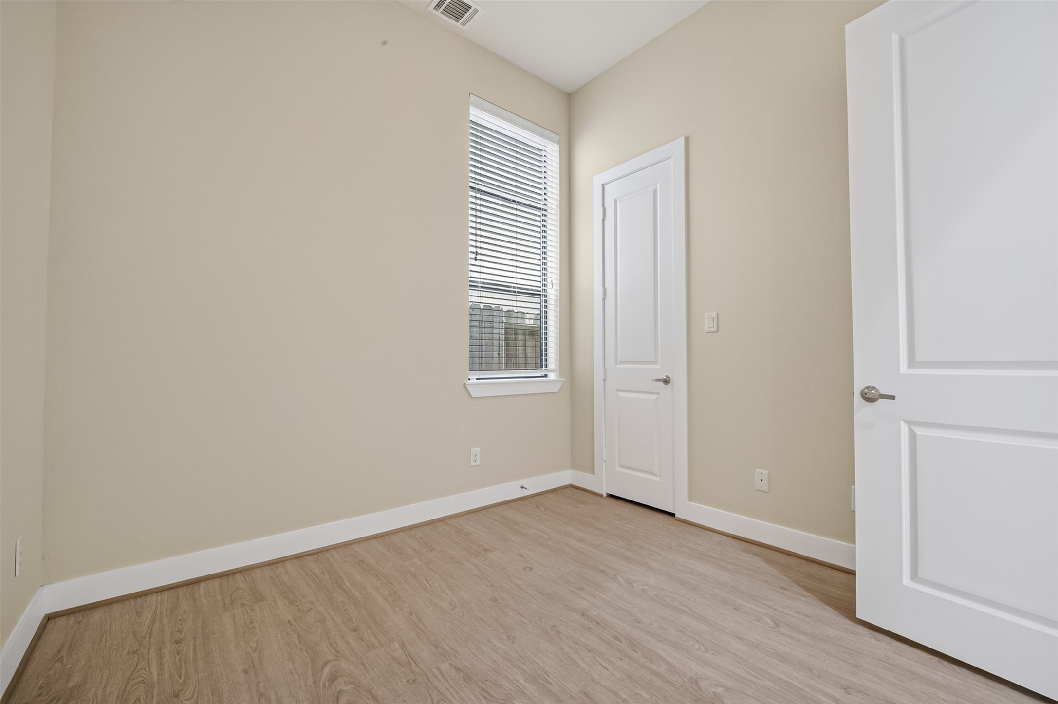 Bright and inviting room with sleek LVP flooring, neutral walls, and a tall window that offers ample natural light, perfect for a cozy retreat or functional office space.