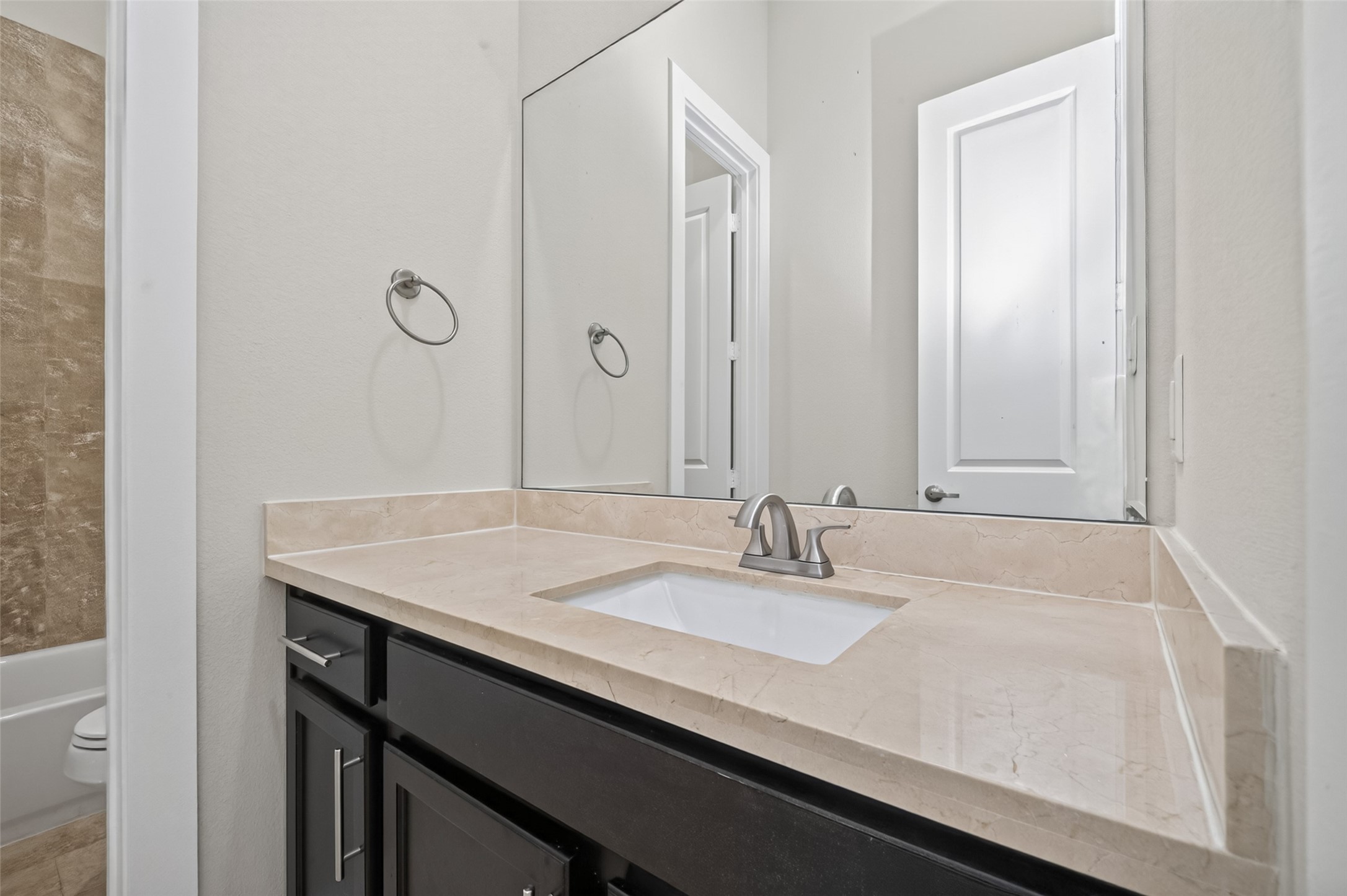 Modern bathroom featuring a sleek vanity with a polished marble countertop, elegant undermount sink, and chrome faucet, complemented by a large mirror and neutral tones.