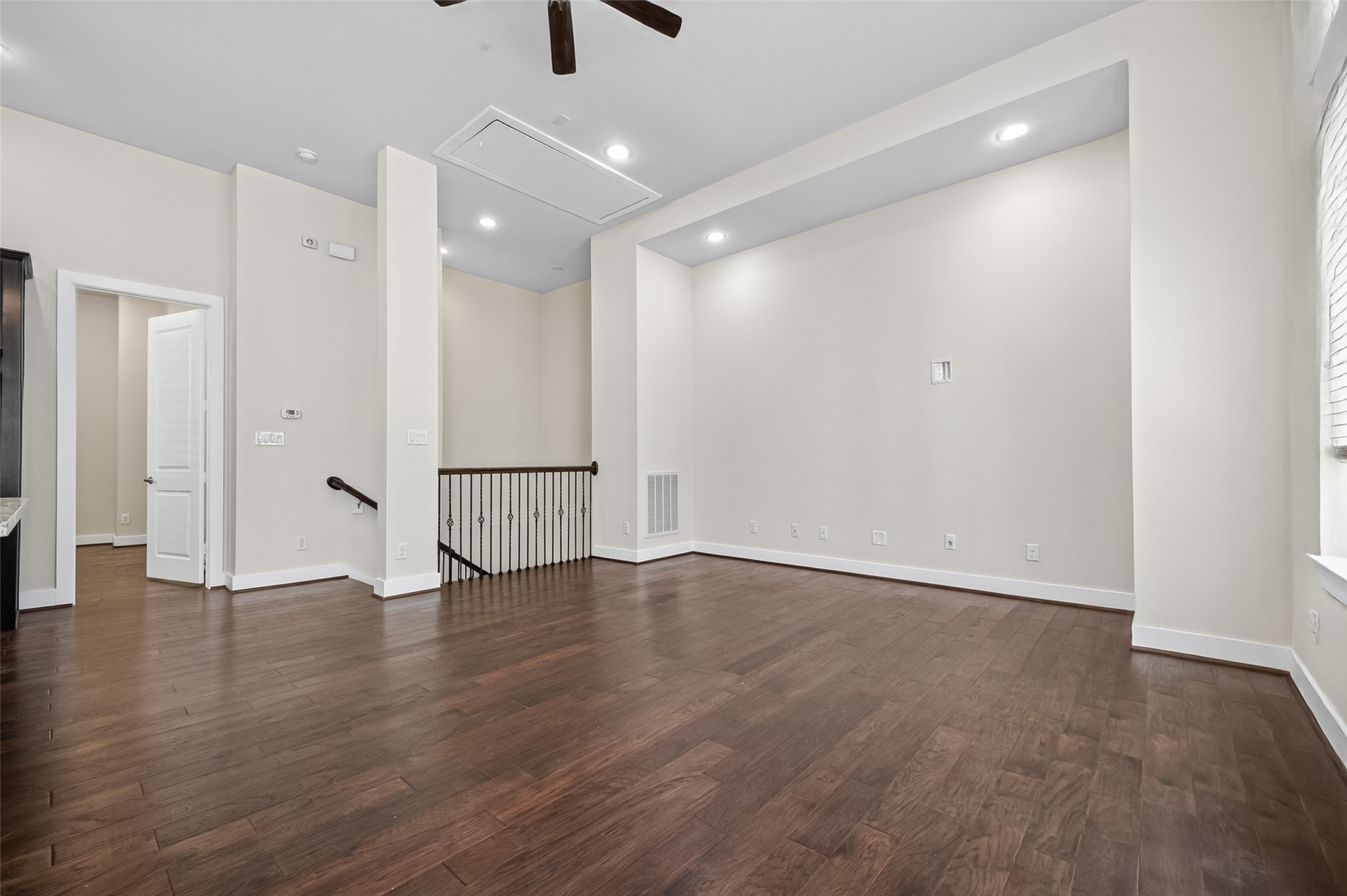 Spacious living area with elegant hardwood floors, recessed lighting, and plenty of natural light from large windows, perfect for relaxation or entertaining.