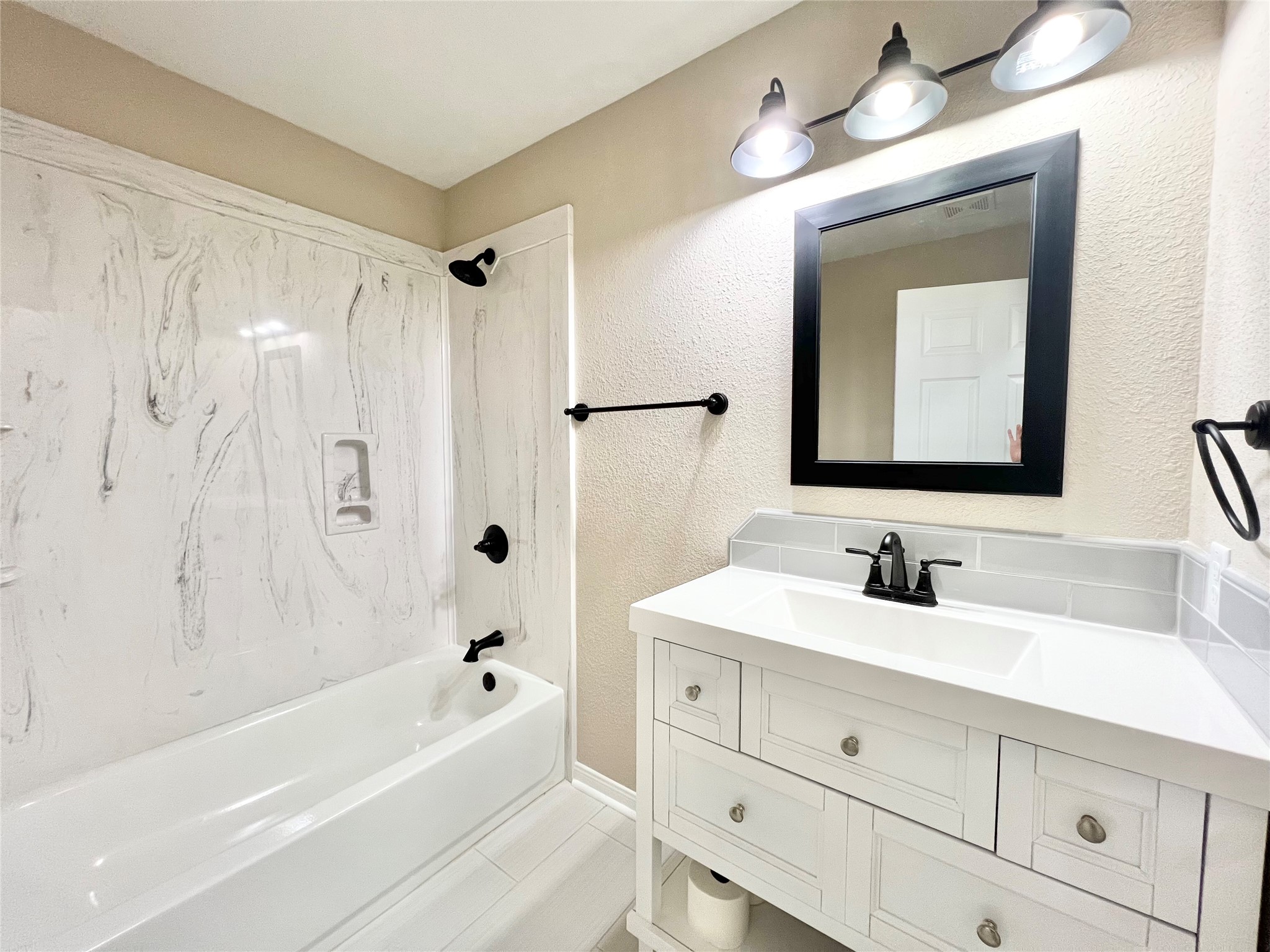 Guest bathroom has a tub/shower combo and large sink/vanity with extra storage space to the left of the shower.