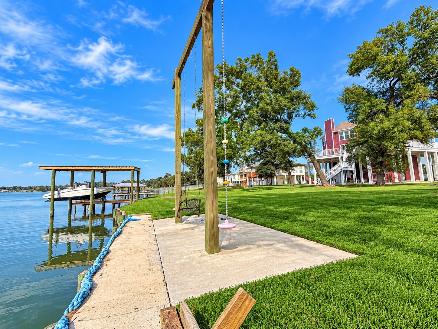 Lakeside living at its finest with a private boat dock, lush lawn, and a charming swing set, perfect for relaxing by the water.