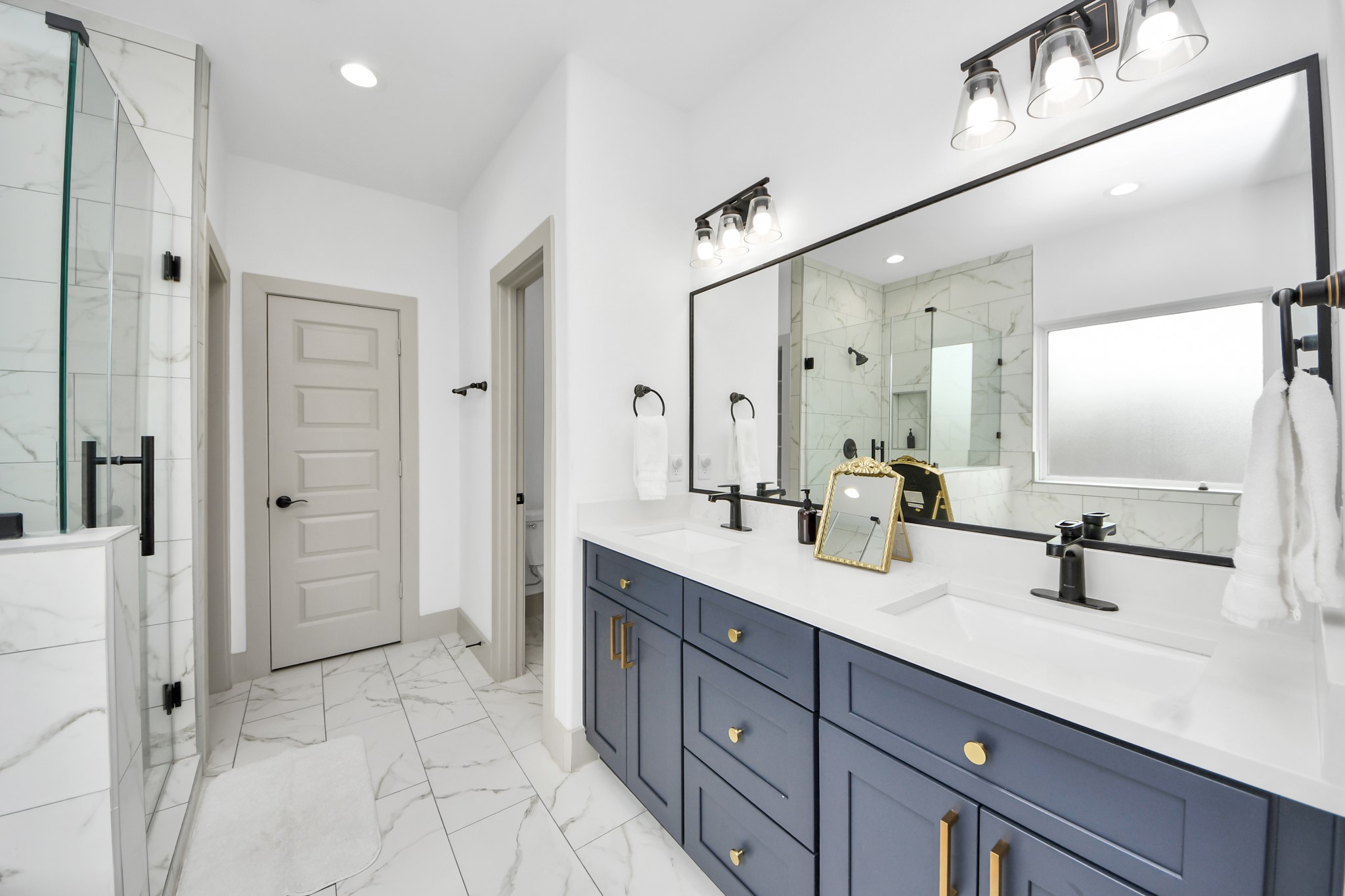 Contemporary primary bathroom featuring modern fixtures, generous vanity space, and clean designer finishes.