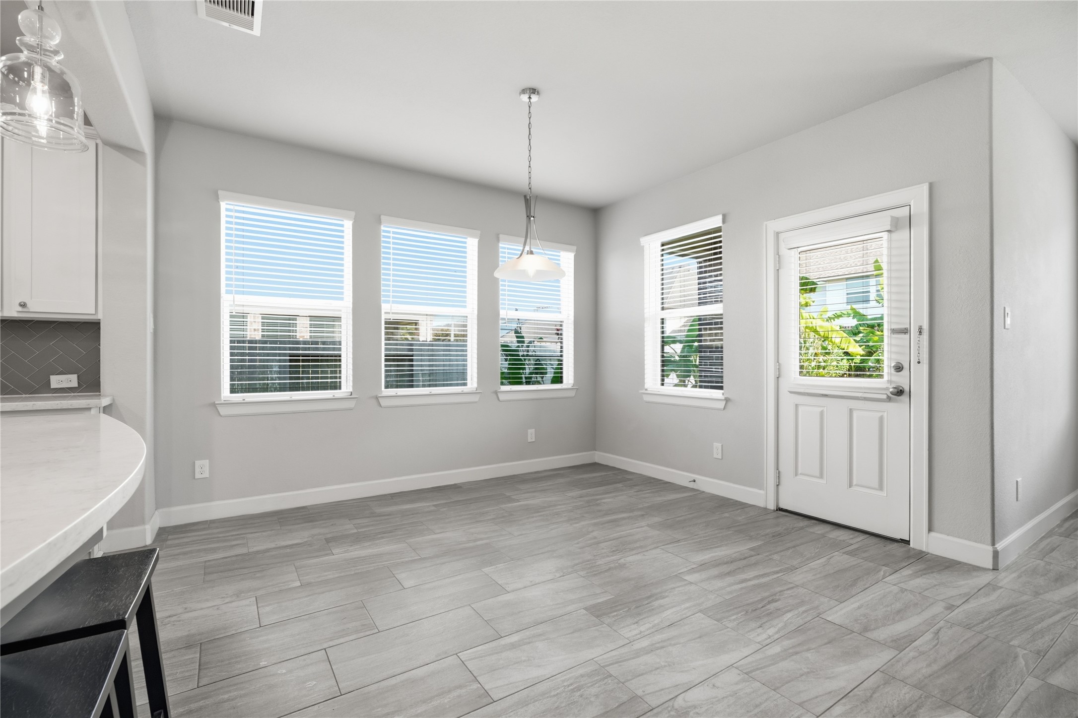 Bright breakfast area surrounded by windows, offering plenty of natural light and a convenient space for everyday dining just off the kitchen.