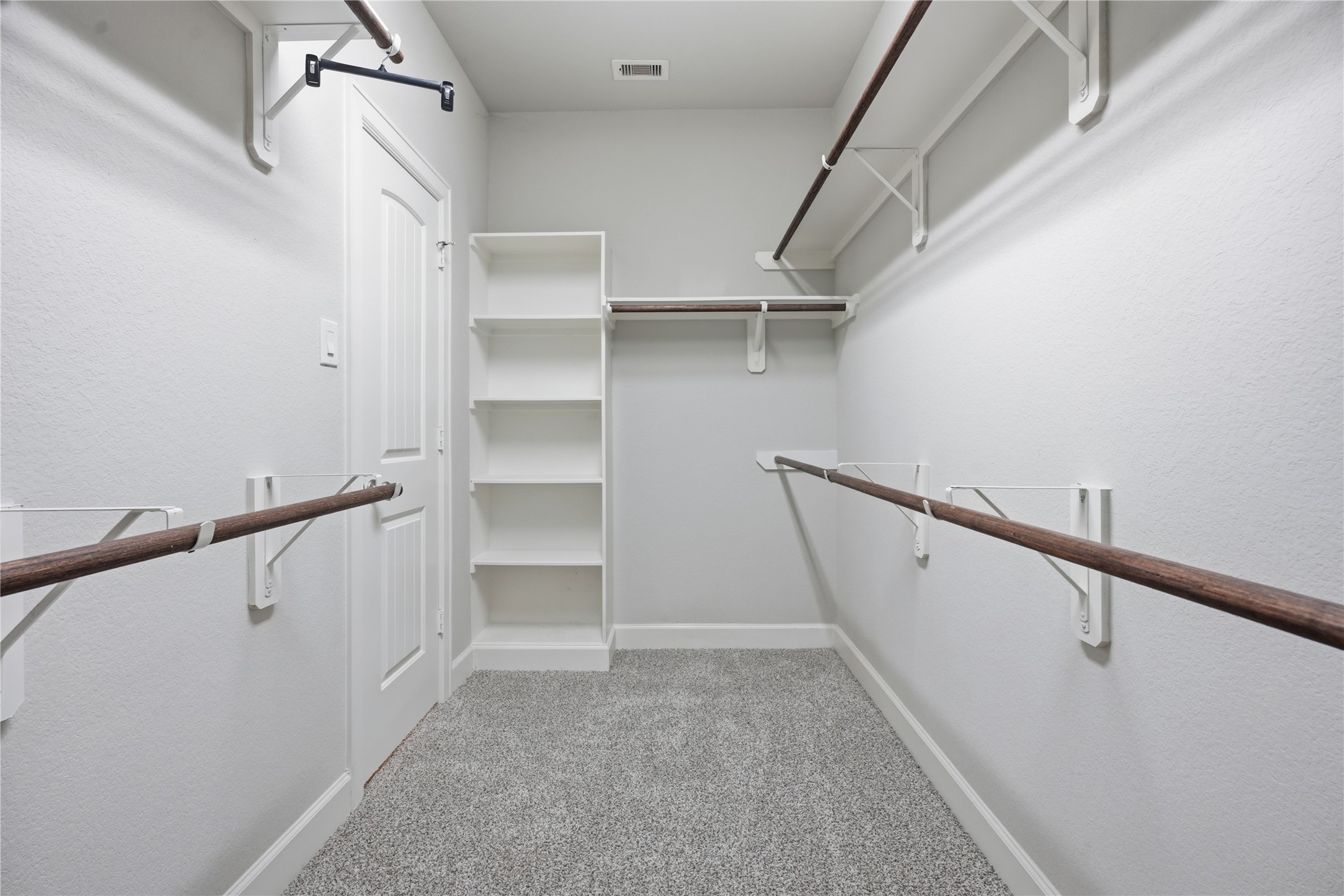 Large walk-in primary closet offers abundant hanging space and built-in shelving for added organization and storage.