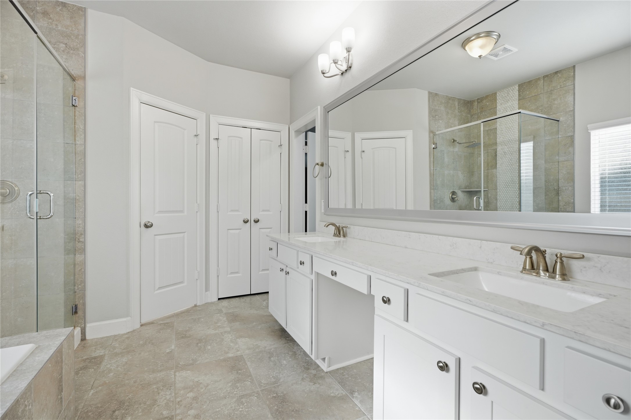 Spacious primary bathroom featuring dual vanities, updated fixtures, and plenty of counter and storage space.