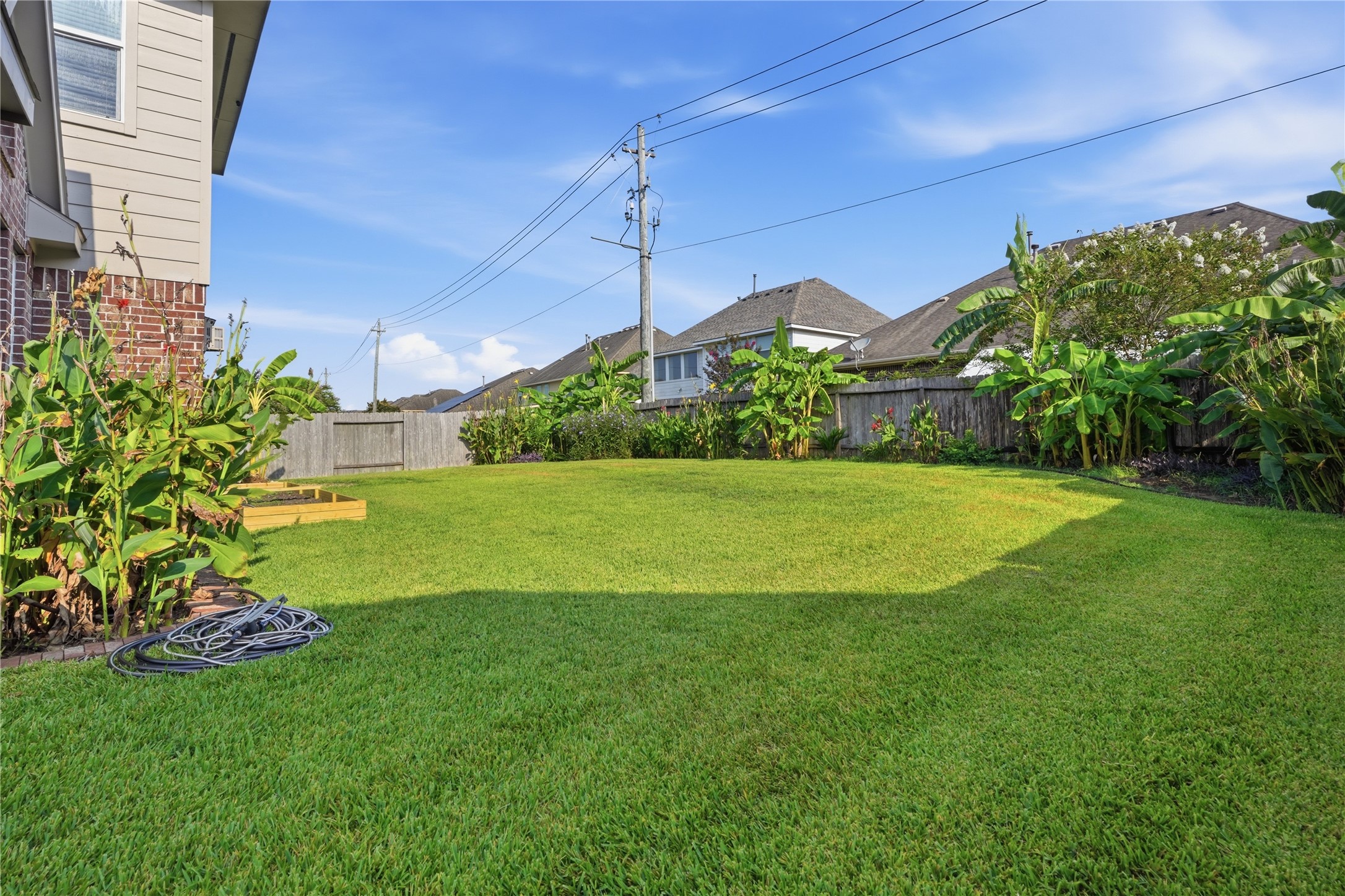 Another view of the backyard highlights the open lawn, established tropical landscaping, and plenty of outdoor space to enjoy.