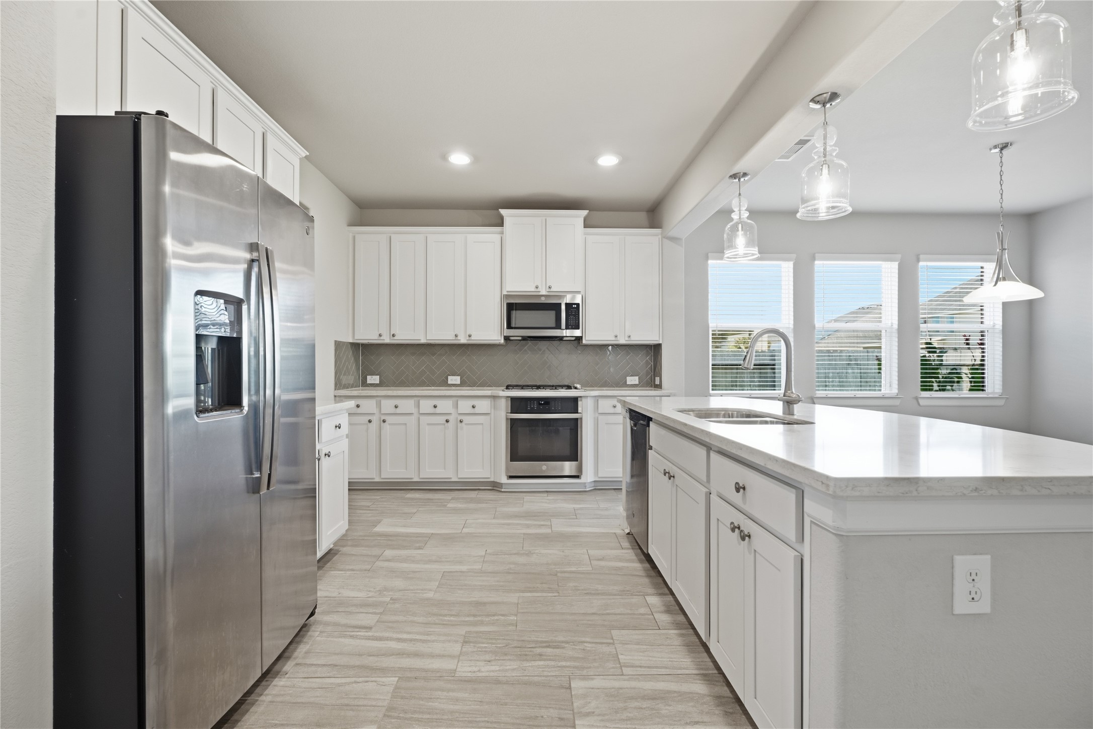 The kitchen flows seamlessly into the breakfast area, with large windows bringing in natural light and offering views of the backyard.