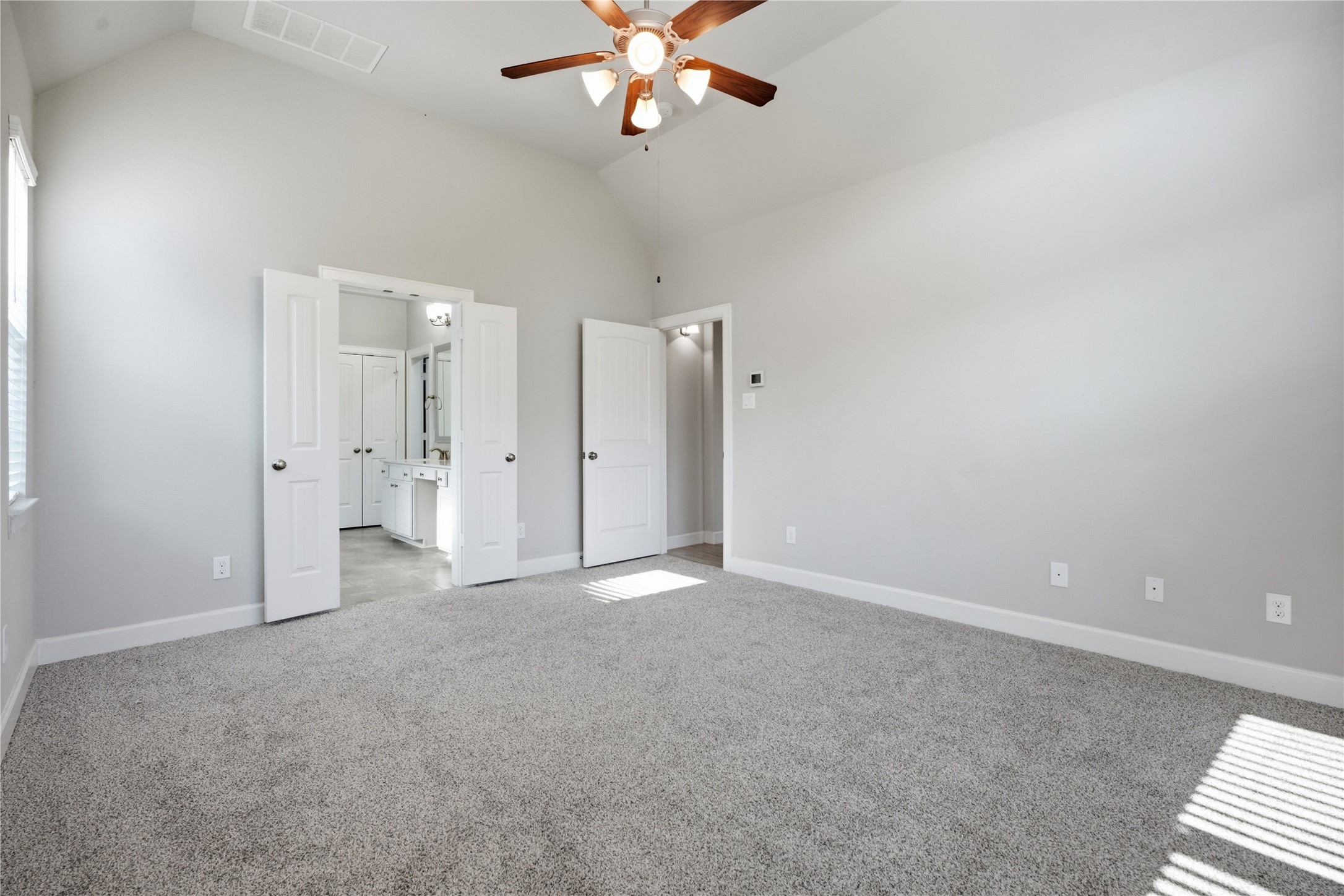 Another view of the primary suite highlights the generous room size and direct access to the private primary bathroom.