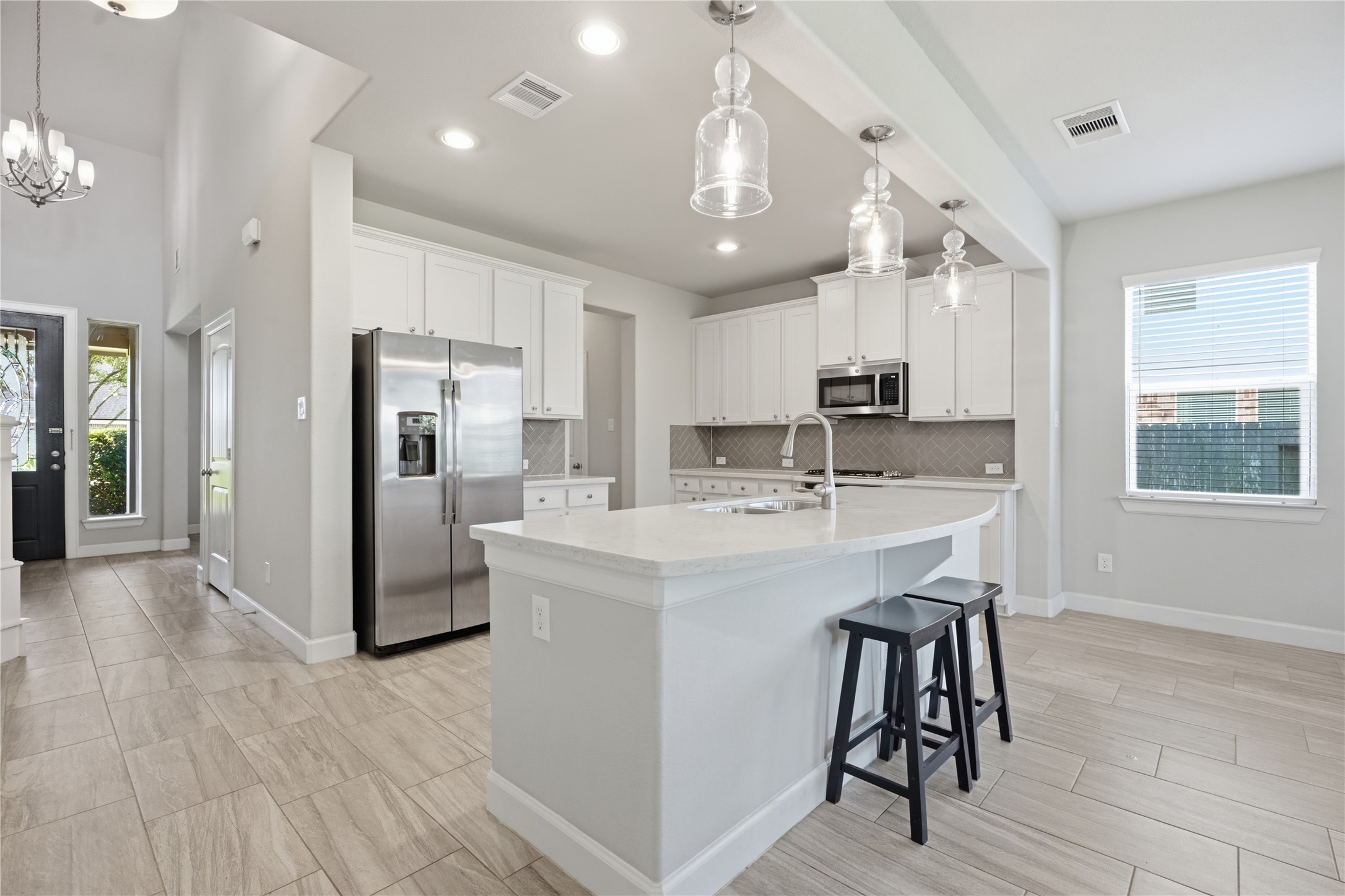 Another view of the kitchen highlights the expansive island with bar seating and plenty of workspace for cooking, serving, and gathering.