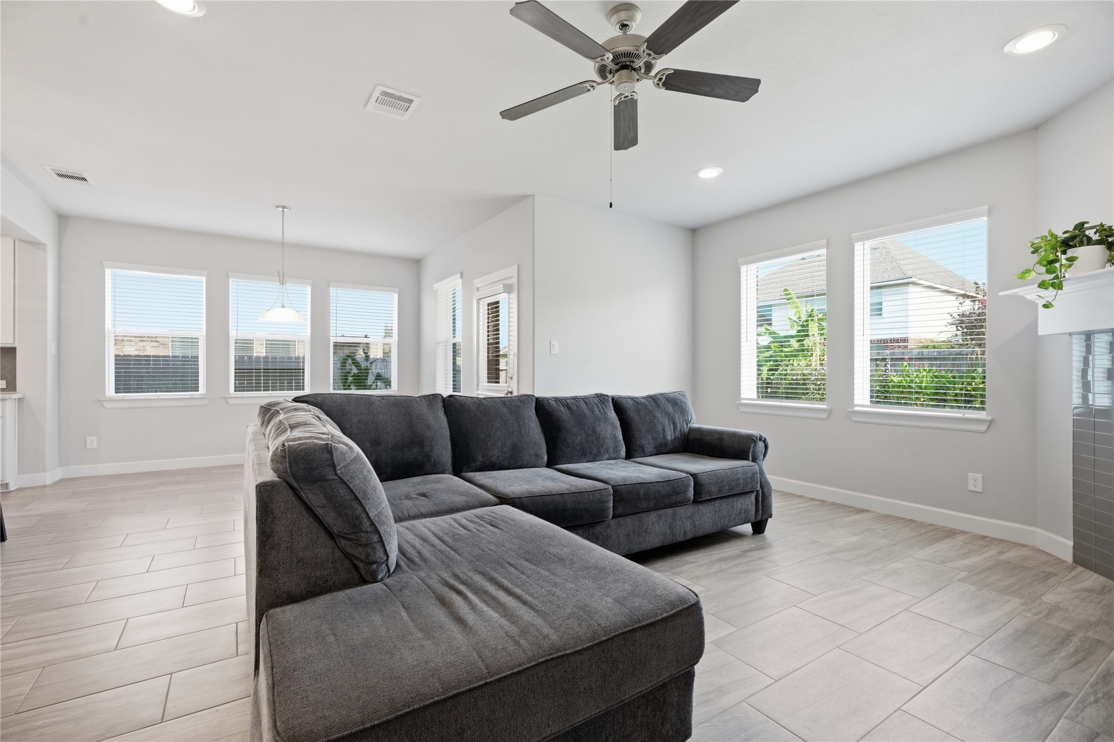 Spacious living room featuring tile flooring, a fireplace, recessed lighting, and plenty of natural light from the surrounding windows.