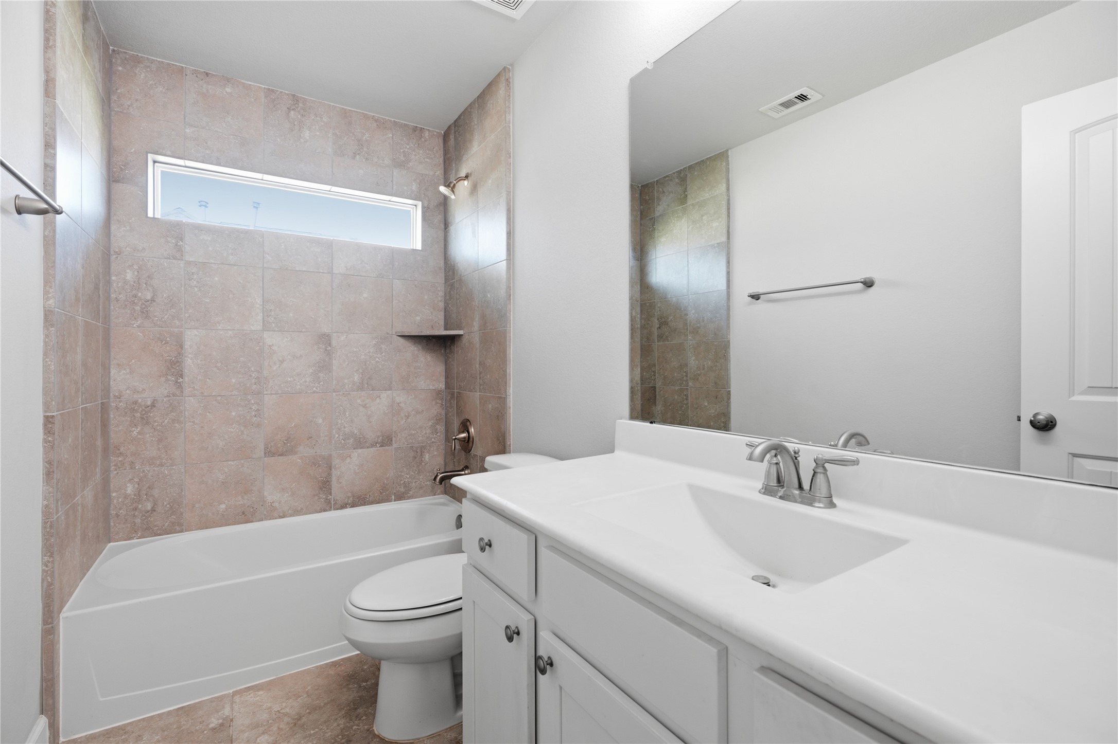 Additional upstairs bedroom featuring a large window, natural light, and convenient access to the nearby full bathroom and game room.