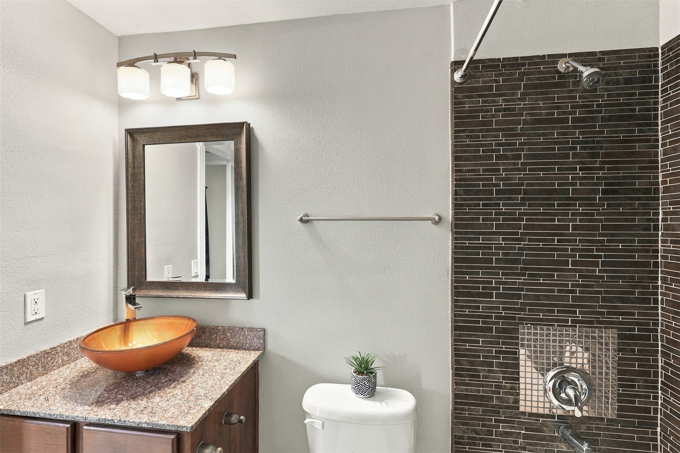 Modern bathroom featuring a stylish vessel sink, granite countertop, and sleek dark tile shower for a contemporary touch.