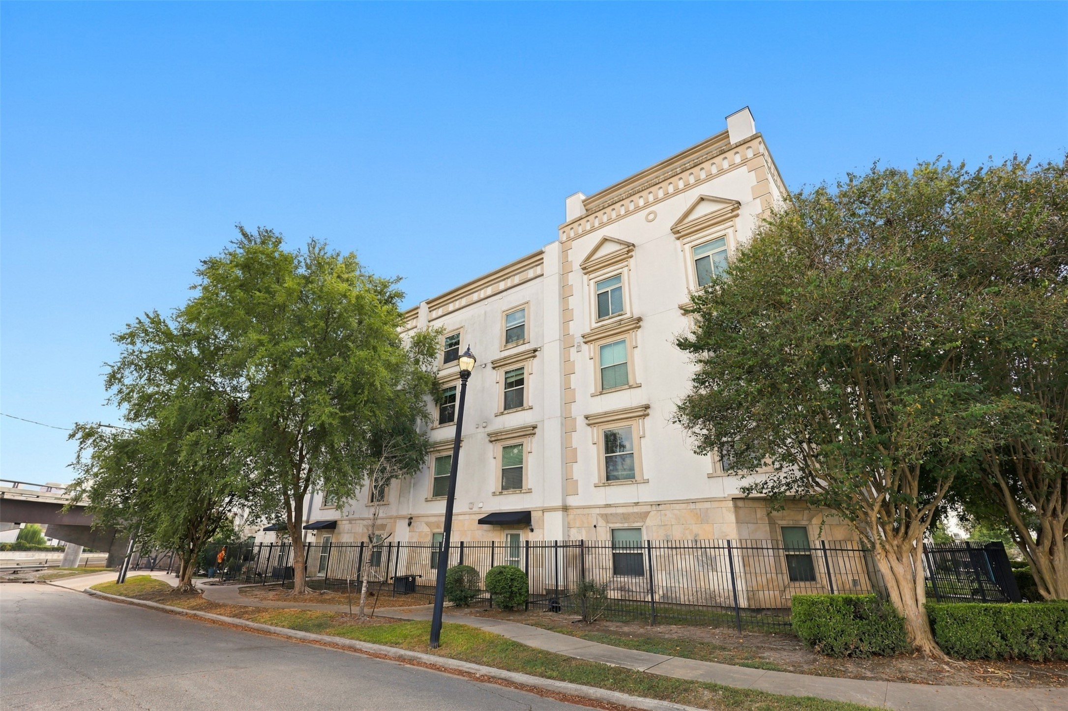 Elegant multi-story building with classic architectural details, surrounded by lush trees and a secure gated entrance. Elegant multi-story building with classic architectural details, surrounded by lush trees and a secure gated entrance.