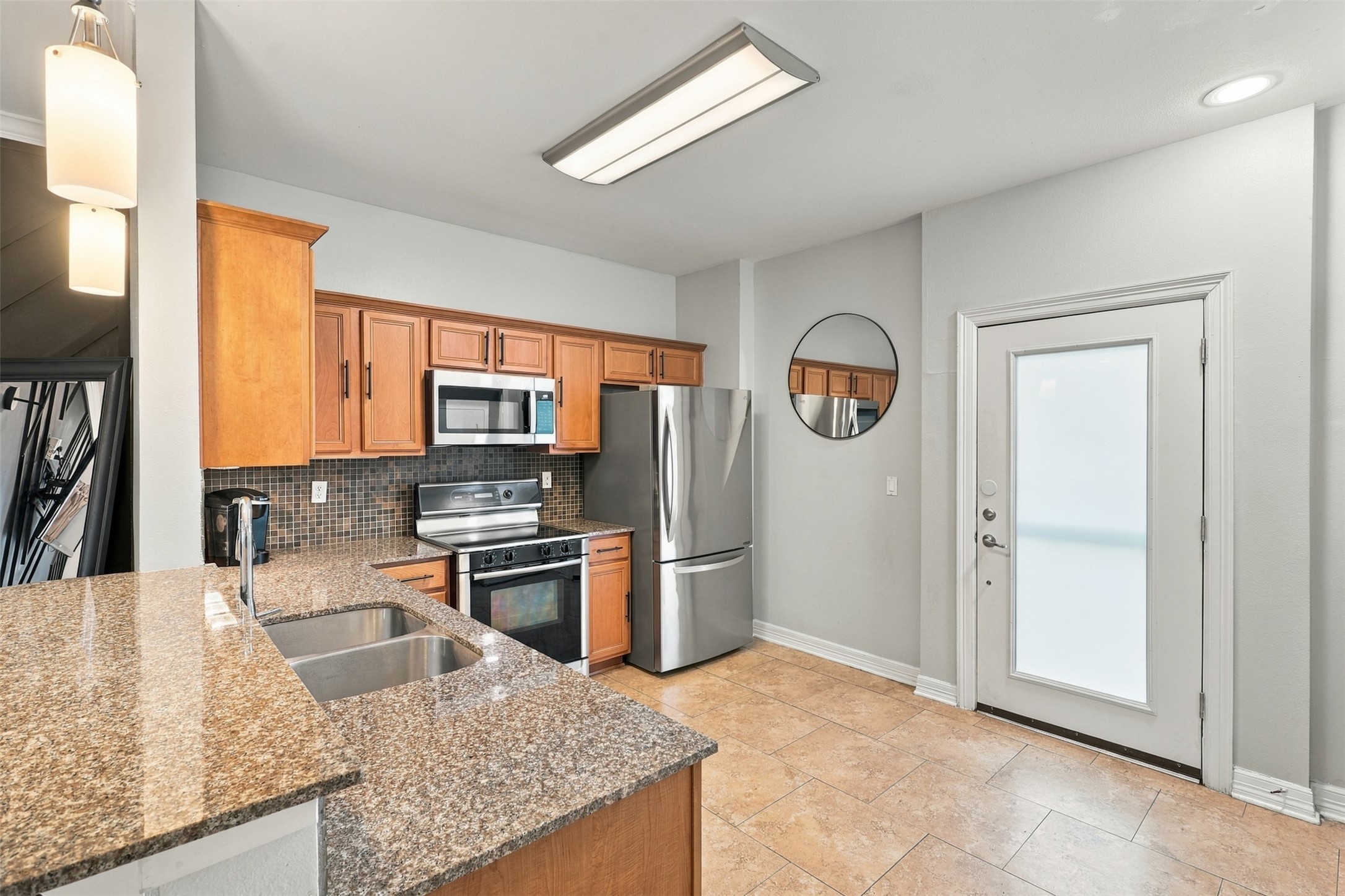 Modern kitchen with stainless steel appliances, granite countertops, and warm wood cabinetry, offering a sleek and inviting cooking space.