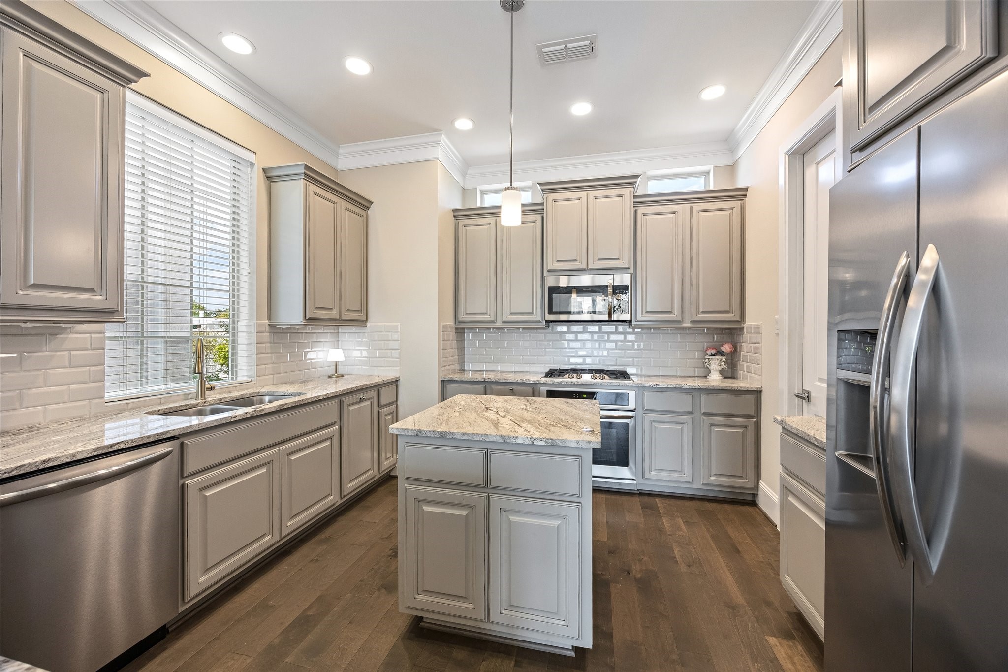 Another perspective of the beautifully appointed kitchen highlighting the stainless steel Frigidaire appliance package including gas cooktop, convection oven, built-in microwave, dishwasher & French door refrigerator included! Beautiful granite countertops, subway tile backsplash & abundant cabinet storage provide excellent functionality. Thoughtful layout offers ample space for cooking, serving & entertaining!