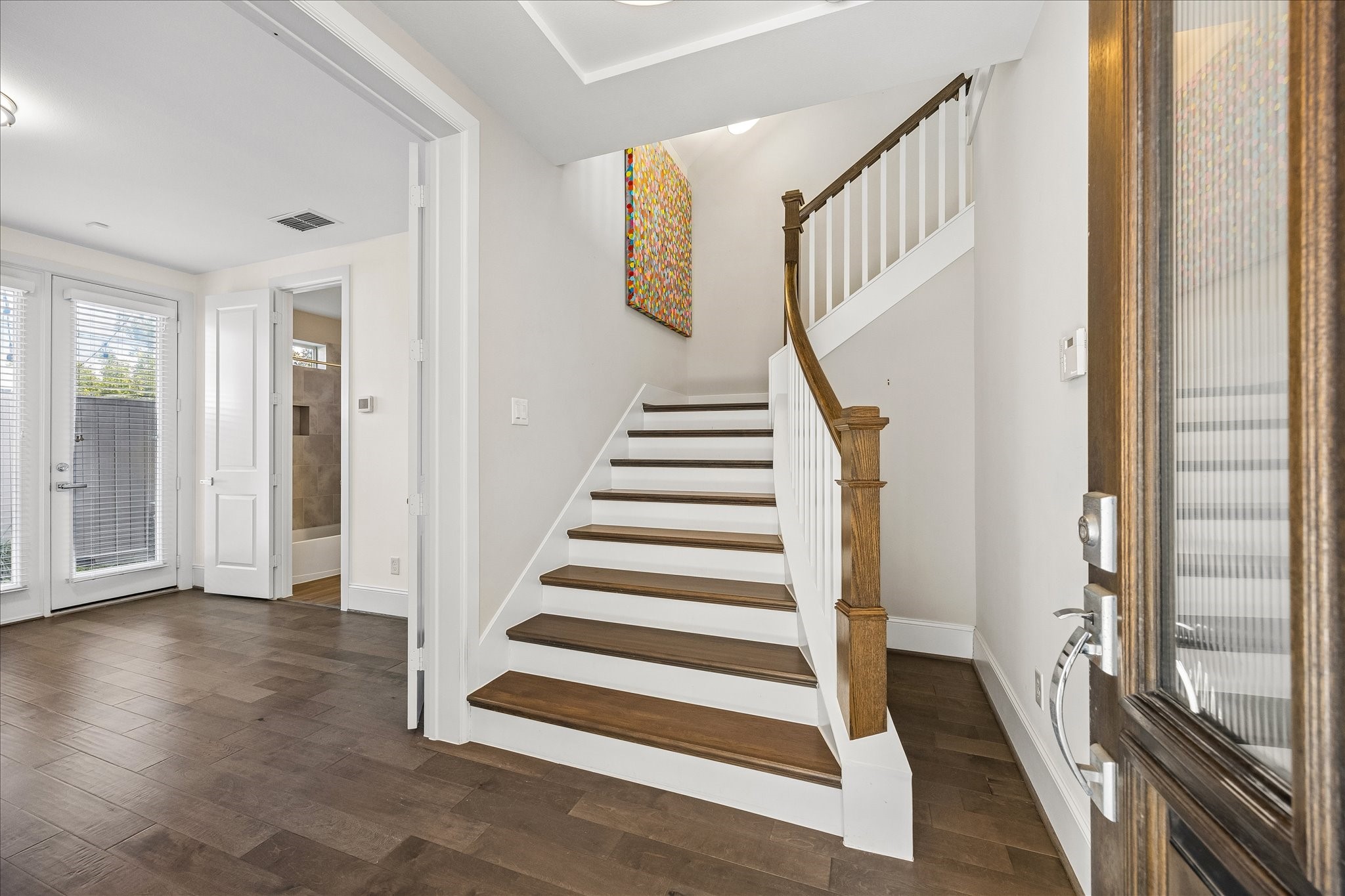 Welcoming 1st floor entry featuring decorative pendant lighting, staircase w/ beautiful light fixtures & convenient access to attached 2-car garage on the right. Double doors  on your left lead to spacious 1st floor secondary bedroom w/ private en suite bath & walk-in closet. Flexible guest bedroom could also make an ideal home office, gym; you name it! Staircase leads to the expansive 2nd floor living spaces!