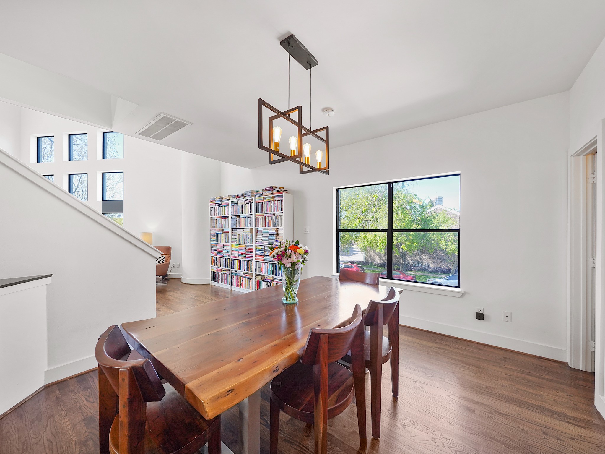 This bright dining area features modern lighting, large windows for natural light, and a cozy reading nook with a bookshelf, creating a warm and inviting atmosphere. This bright dining area features modern lighting, large windows for natural light, and a cozy reading nook with a bookshelf, creating a warm and inviting atmosphere.