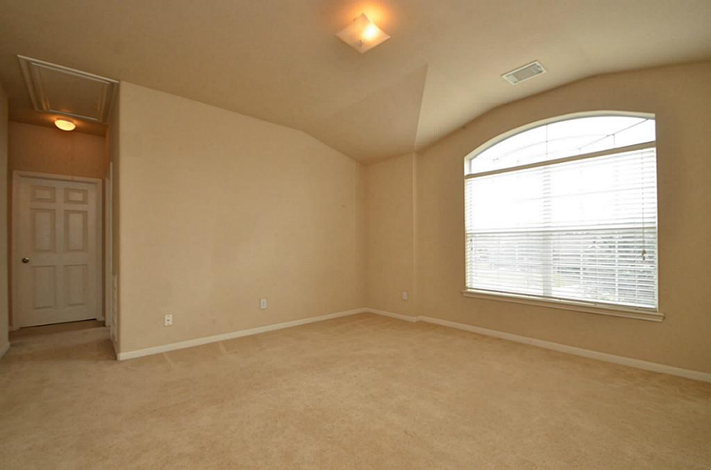 This bedroom features cozy carpeting and a large window that floods the space with natural light.