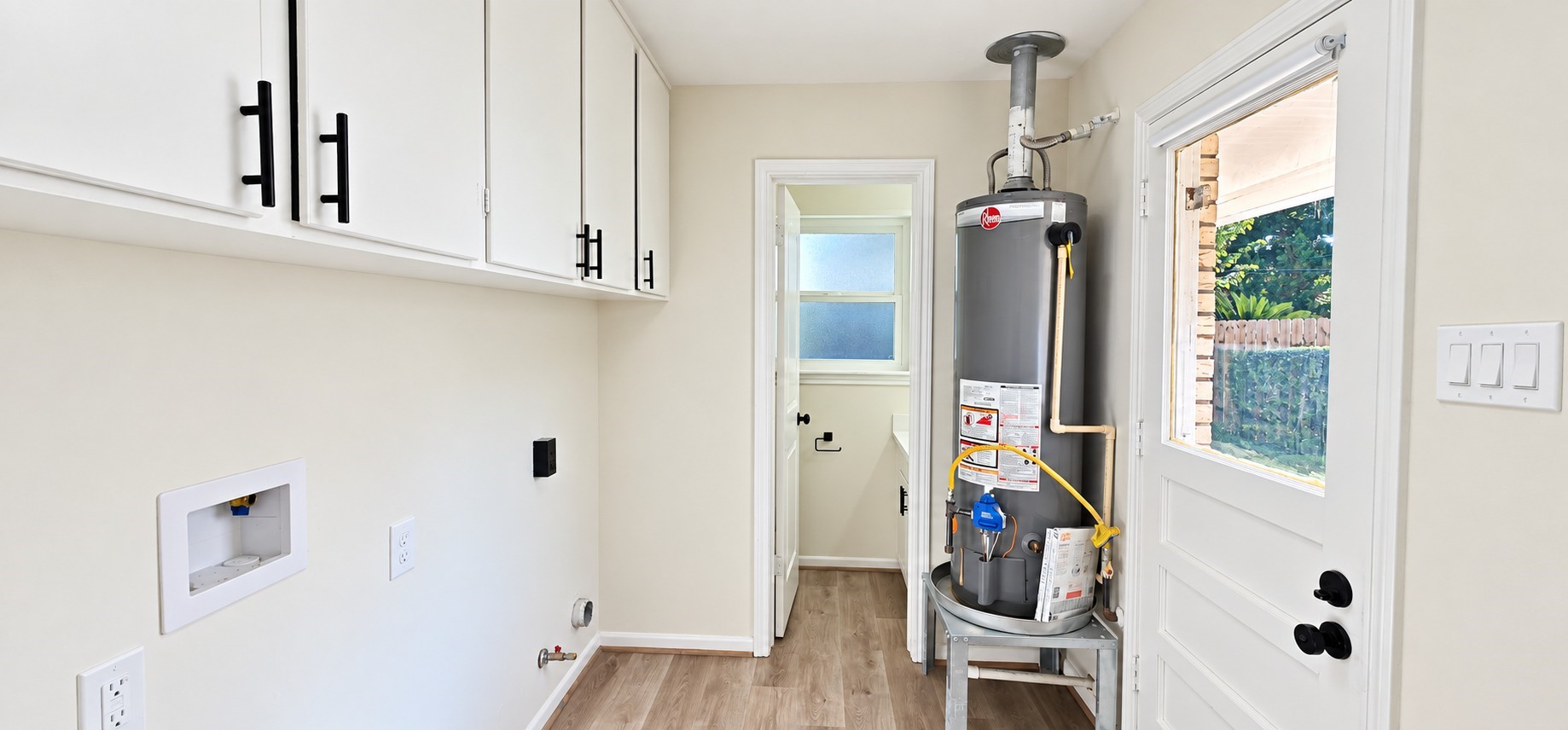 Dedicated laundry room offers built-in upper cabinetry, washer/dryer connections, and convenient backyard access.