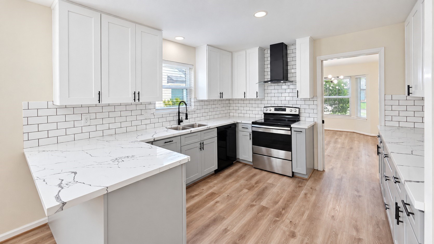 Updated kitchen features crisp white cabinetry, contrasting lower cabinets, black hardware, and stainless appliances.