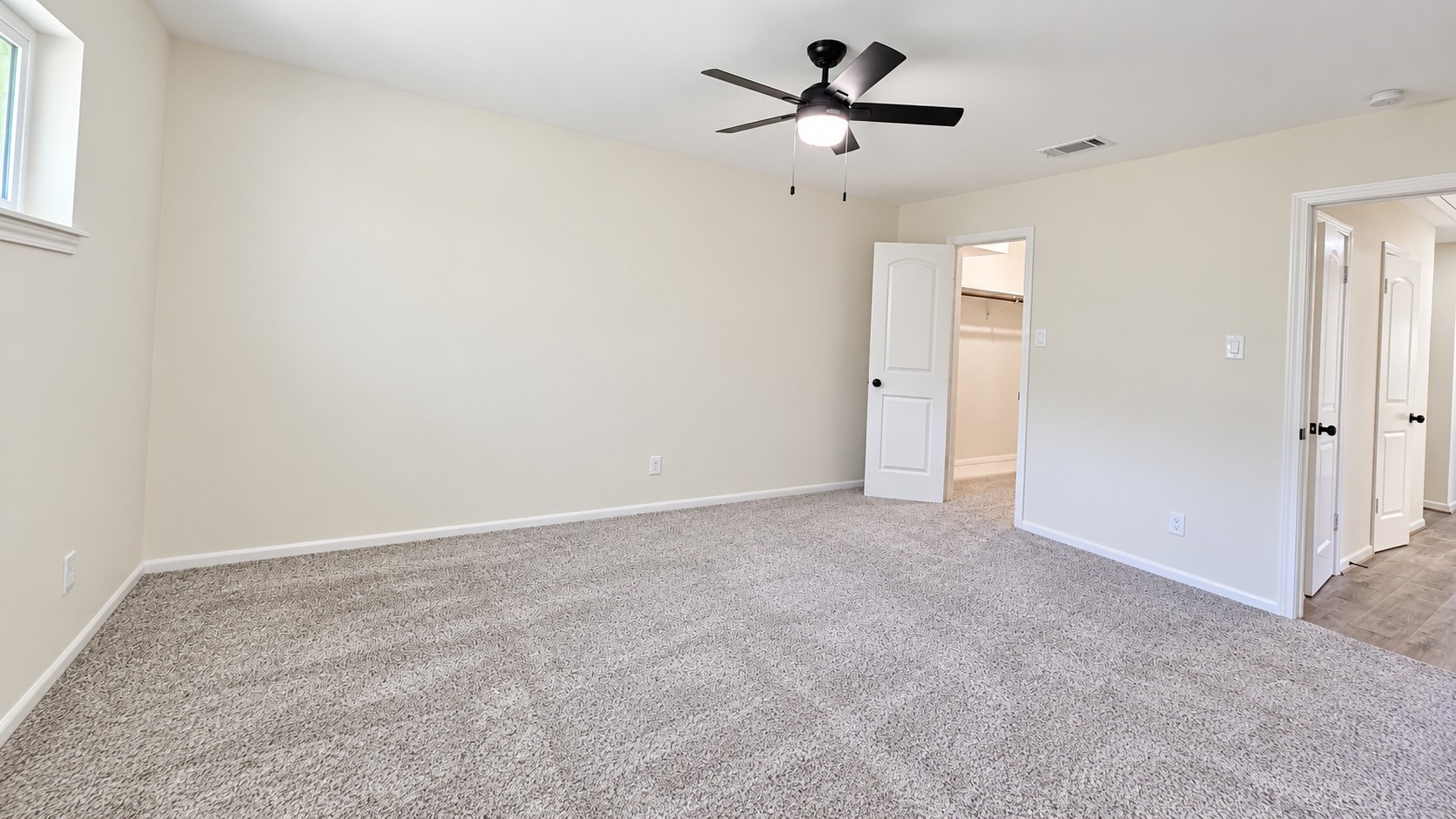 Alternate view of the spacious primary bedroom highlights excellent wall space and easy access to the adjoining areas.
