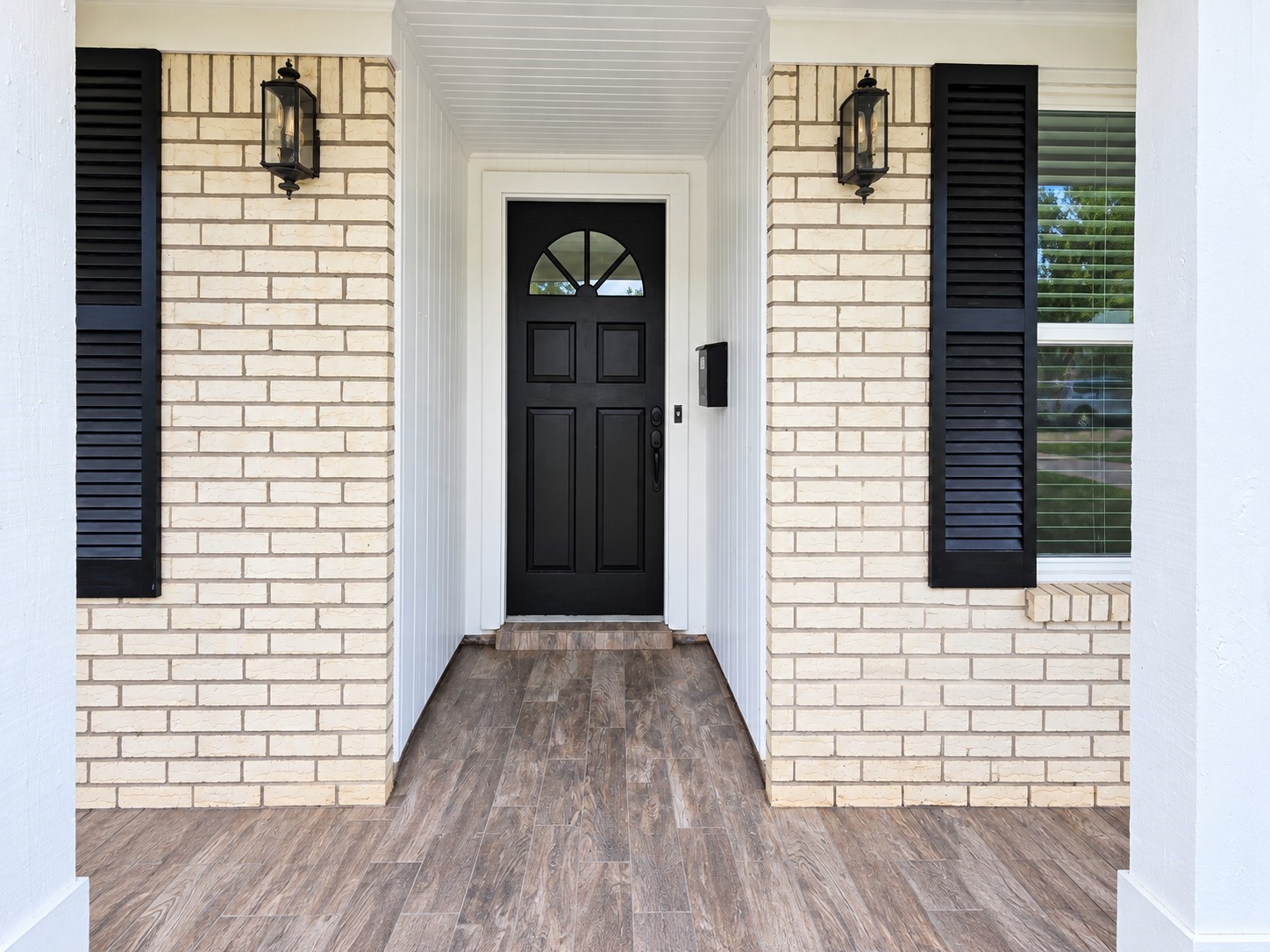 Covered front porch leads to a striking black entry door framed by classic brick and black accents. Covered front porch leads to a striking black entry door framed by classic brick and black accents.