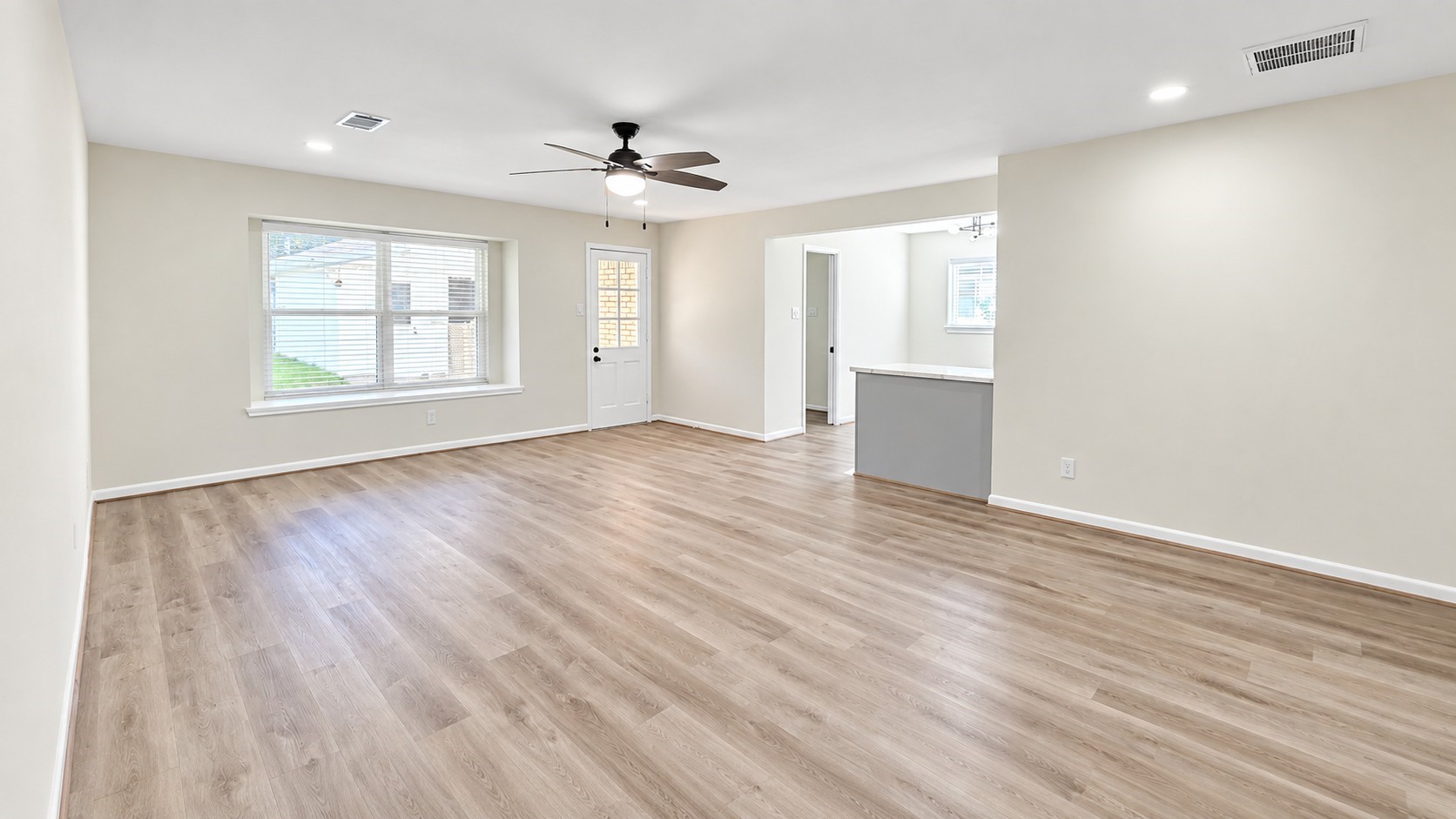 Expansive living area with updated flooring, recessed lighting, ceiling fan, and an open connection to the kitchen.