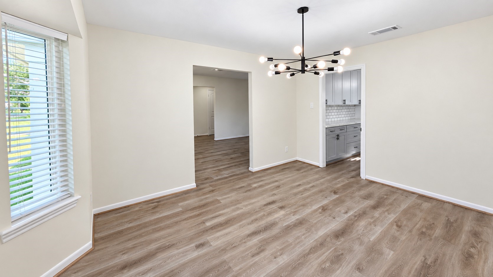 Dedicated dining room with contemporary statement lighting and abundant natural light from the bay windows.