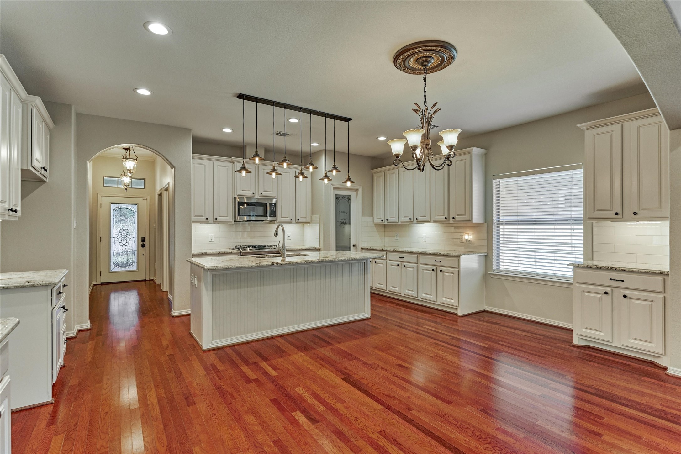 The center island with decorative lighting provides additional seating and counter space.