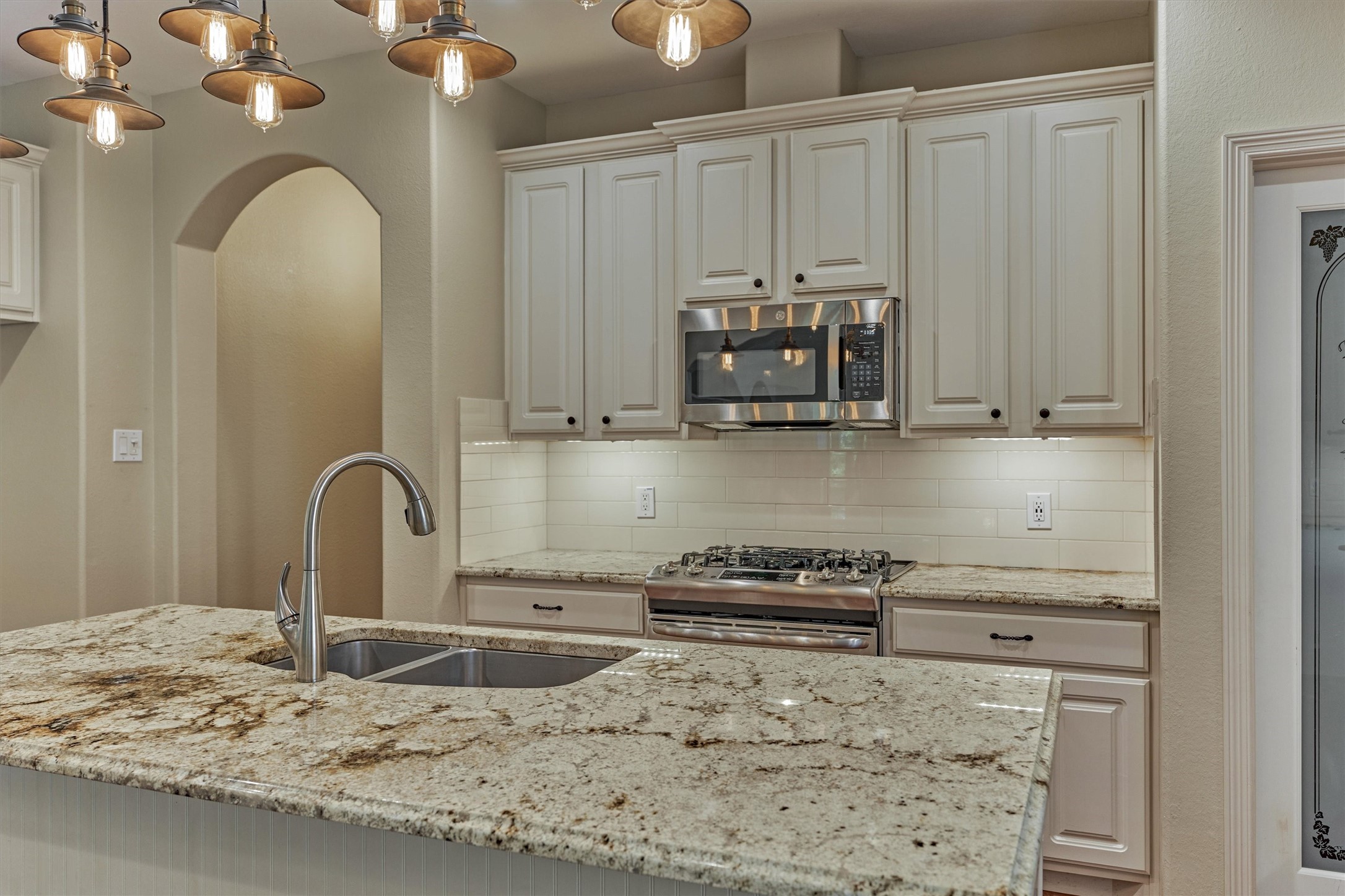 Under counter lighting, granite countertops with decorative edge and subway tile backsplash are a few designer features of this bright kitchen.