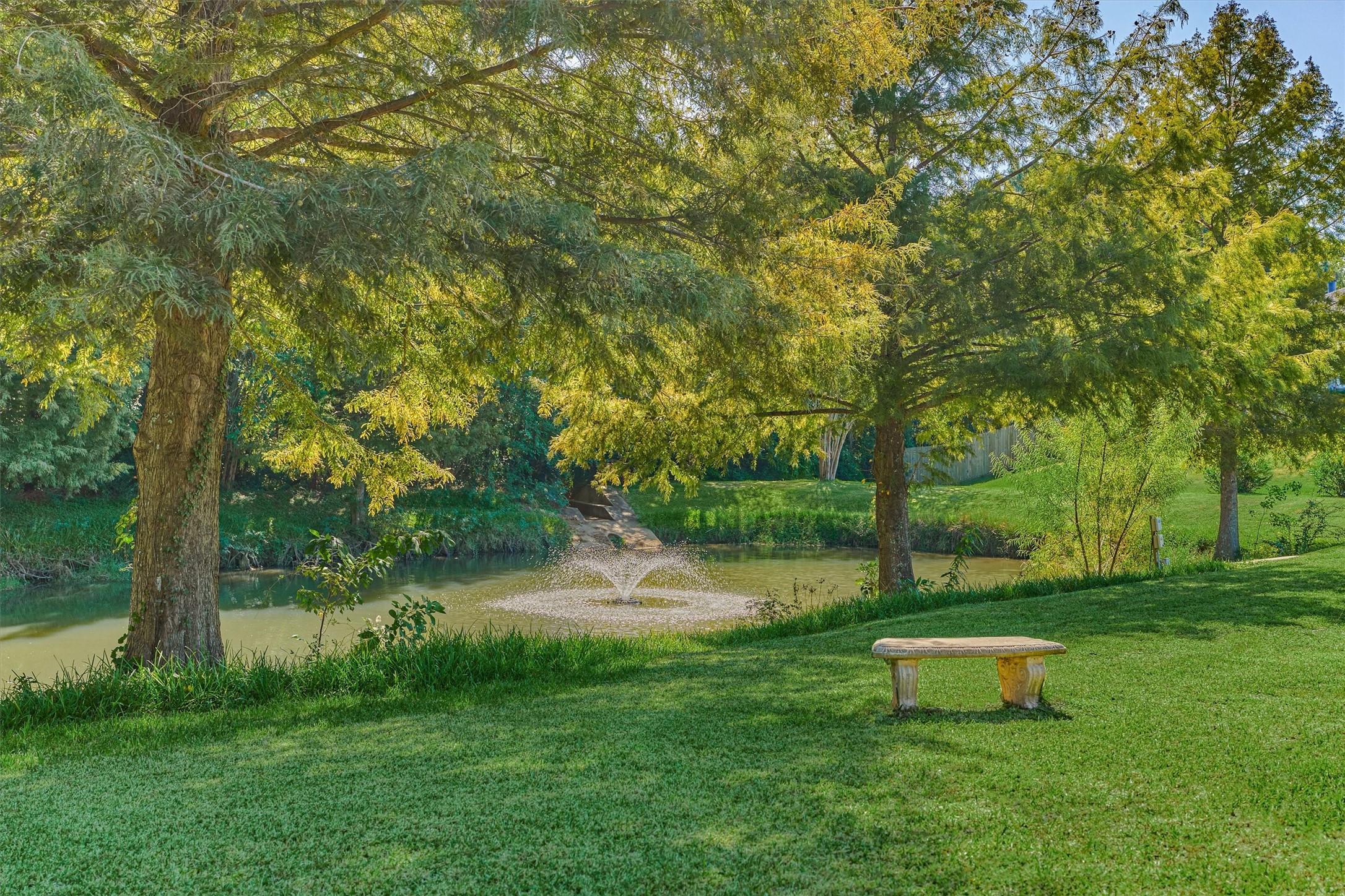 Pond with fountain nearby and bench for a serene, peaceful setting.