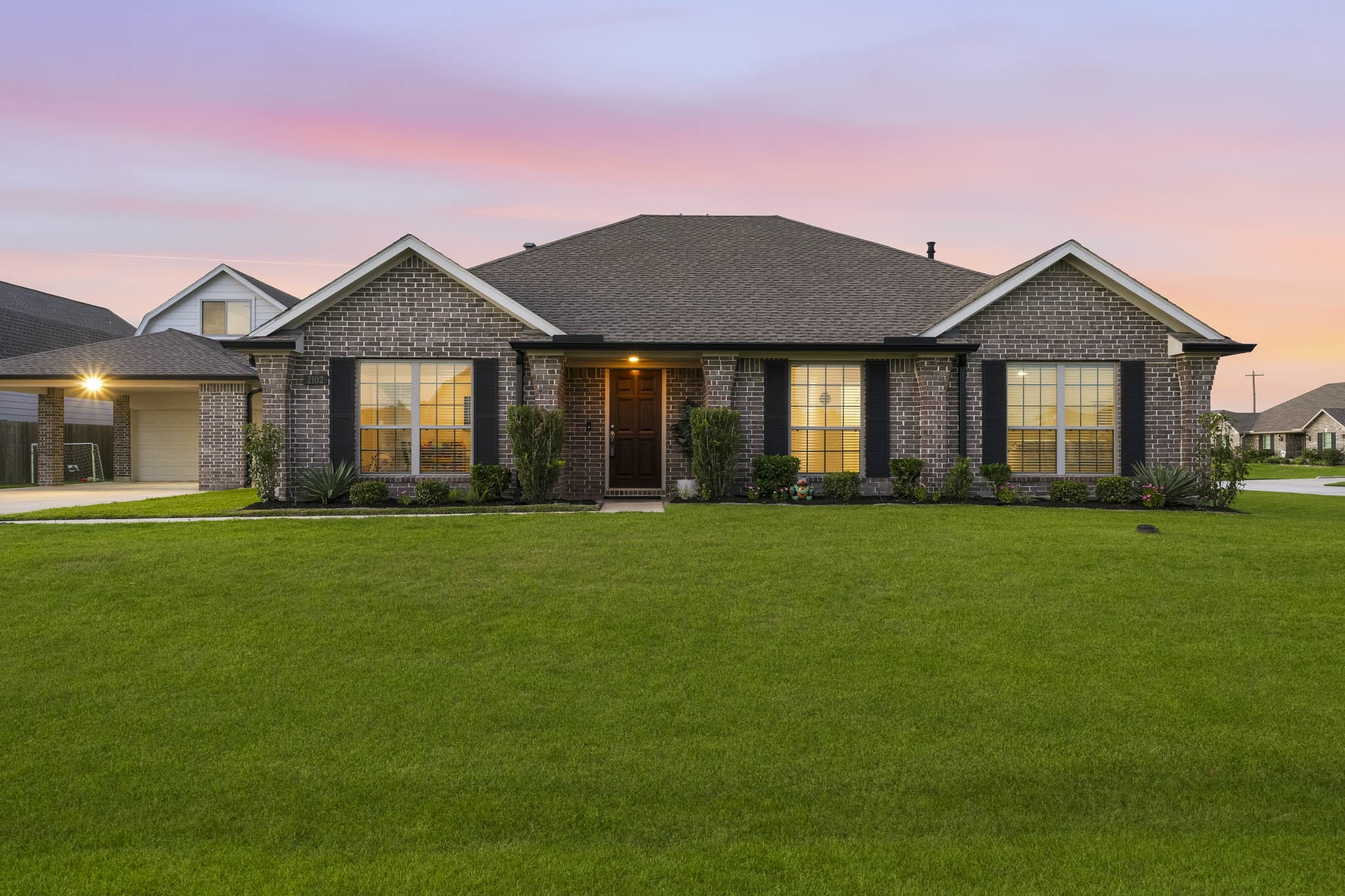 Twilight view of front of home featuring updated landscaping and gutters.