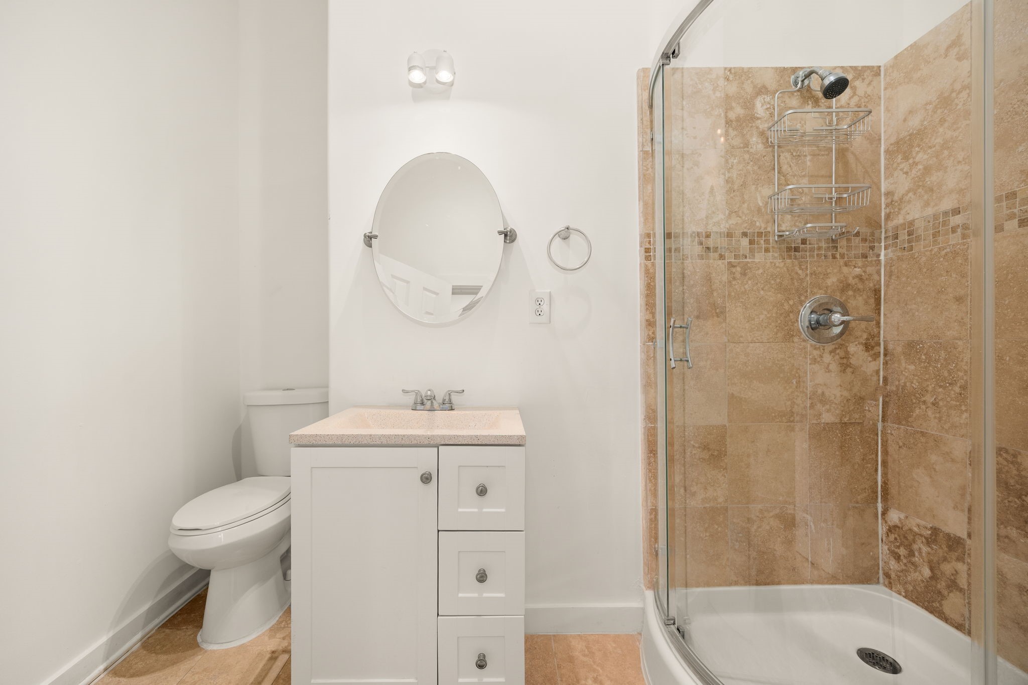 This additional full bathroom, conveniently located off the bonus room accessed through the garage, features warm stone tile, a glass-enclosed shower, and timeless finishes, offering added comfort and convenience for guests.